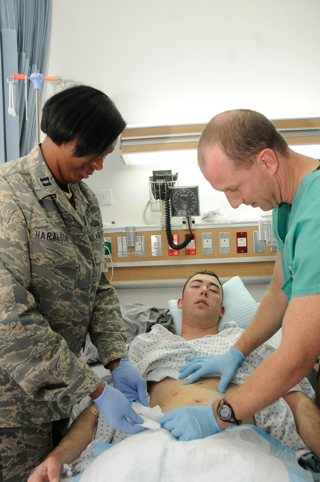 Capt. Deidra Haralson, wounded warrior coordinator assigned to the 379th Expeditionary Medical Group, and Maj. Craig Kolasch, general surgeon assigned to the 379th Expeditionary Medical Group, checks the surgical incisions of a surgical patient Nov. 26, 2008, at an undisclosed air base in Southwest Asia. The 379 EMDG members are responsible for ensuring all injured personnel are receiving the best medical care while they recover from their injuries. Captain Haralson, a native of Alamogordo, N.M., is deployed from the Pentagon, Washington, D.C., and Major Kolasch, a native of Great Falls, Va., is deployed from Keesler Air Force Base, Miss. Both are deployed in support of Operations Iraqi and Enduring Freedom and Joint Task Force-Horn of Africa. (U.S. Air Force photo by Staff Sgt. Darnell T. Cannady/Released)