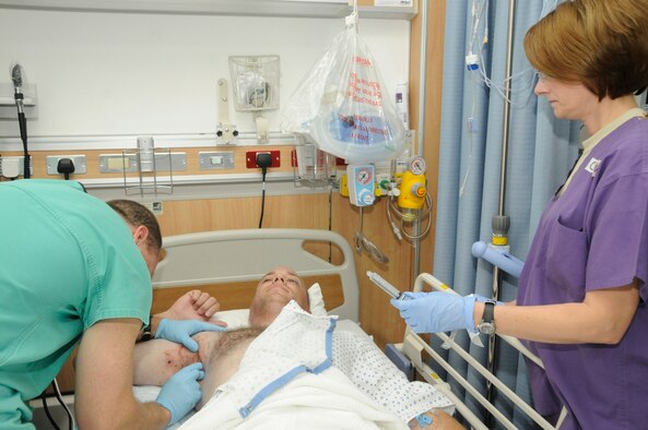 Maj. Craig Kolasch, general surgeon assigned to the 379th Expeditionary Medical Group, changes an injured man's dressing Nov. 26 at the Wounded Warrior Center of Excellence at an air base in Southwest Asia while Capt. Darla Mitten, a registered nurse assigned to the 379th EMDG, assists.  Major Kolasch, a native of Great Falls, Va., is deployed from Keesler Air Force Base, Miss., and Captain Mitten, a native of Brownsburg, Ind., is deployed from the Indiana Air National Guard in Terre Haute. (U.S. Air Force photo/Staff Sgt. Darnell T. Cannady)