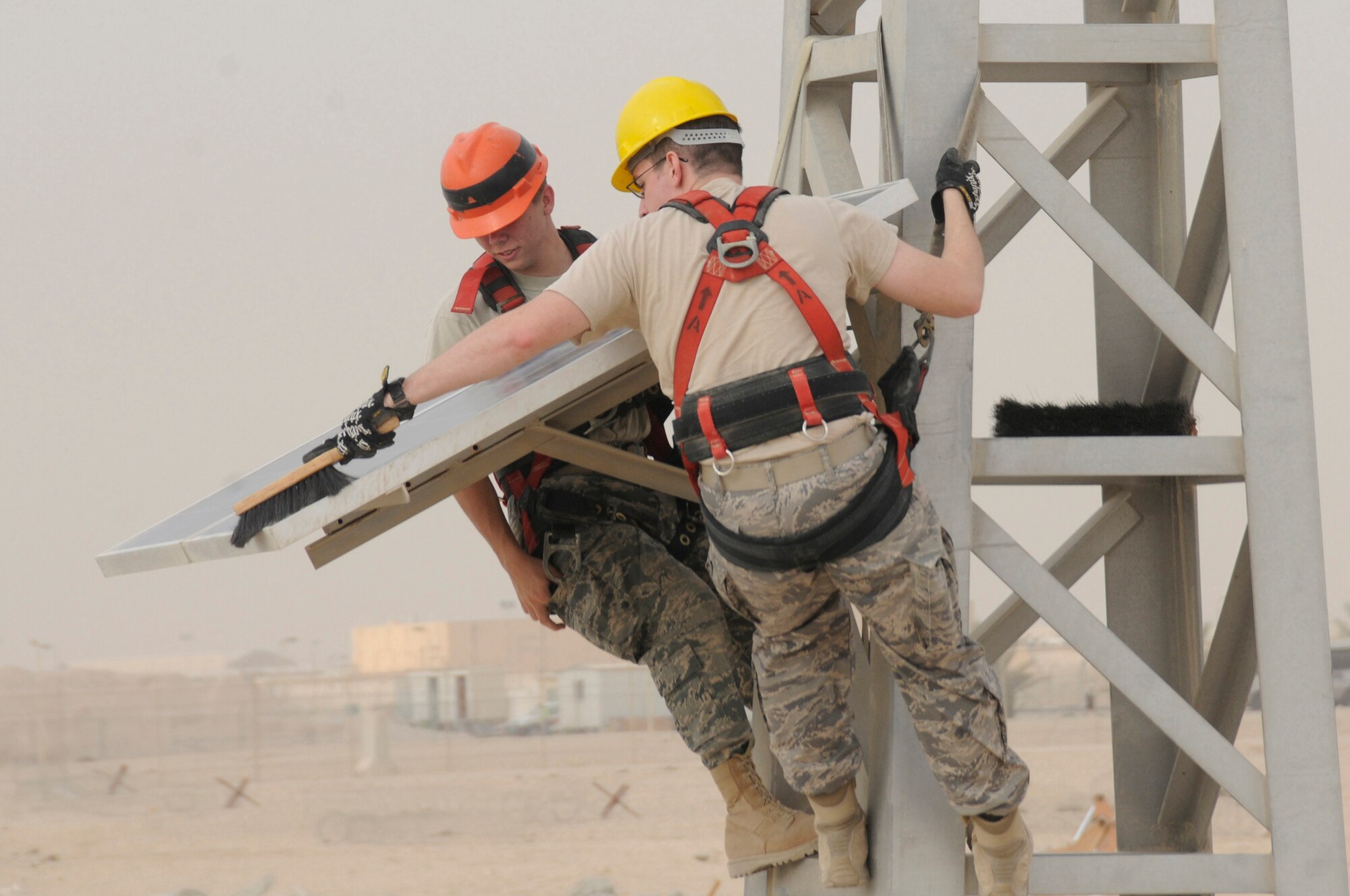 Senior Airman Paul Hunter and Airman 1st Class Jeffrey Hyatt, both radio maintenance technicians assigned to the 379th Expeditionary Communications Squadron, use brushes to clear dust and debris from the solar panel of a giant voice tower Nov. 29, at an undisclosed air base in Southwest Asia.  Airman Hunter, a native of Meridian, Miss., is deployed from Key Field Air National Guard, Miss., and Airman Hyatt, a native of Woodbine, Ga., is deployed from Shaw AFB, S.C.  Both are deployed in support of Operations Iraqi and Enduring Freedom and Joint Task Force-Horn of Africa. (U.S. Air Force photo by Staff Sgt. Darnell T. Cannady/Released)
