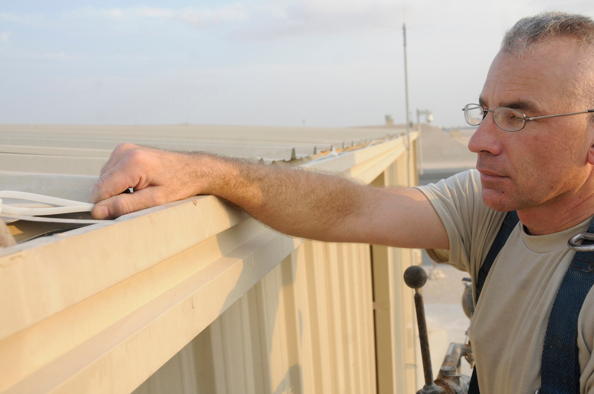 Master Sgt. Michel Senecal, superintendent of Air Terminal Operations assigned to the 8th Expeditionary Air Mobility Squadron, uses zip ties to secure wires of a new flightline security camera Nov. 28, at an undisclosed air base in Southwest Asia. The new security camera will provide a higher view of the activities on the flight line. Sergeant Senecal, a native of Warwick, R.I., is deployed from North Kingston Air National Guard, R.I., in support of Operations Iraqi and Enduring Freedom and Joint Task Force-Horn of Africa. (U.S. Air Force photo by Staff Sgt. Darnell T. Cannady/Released)