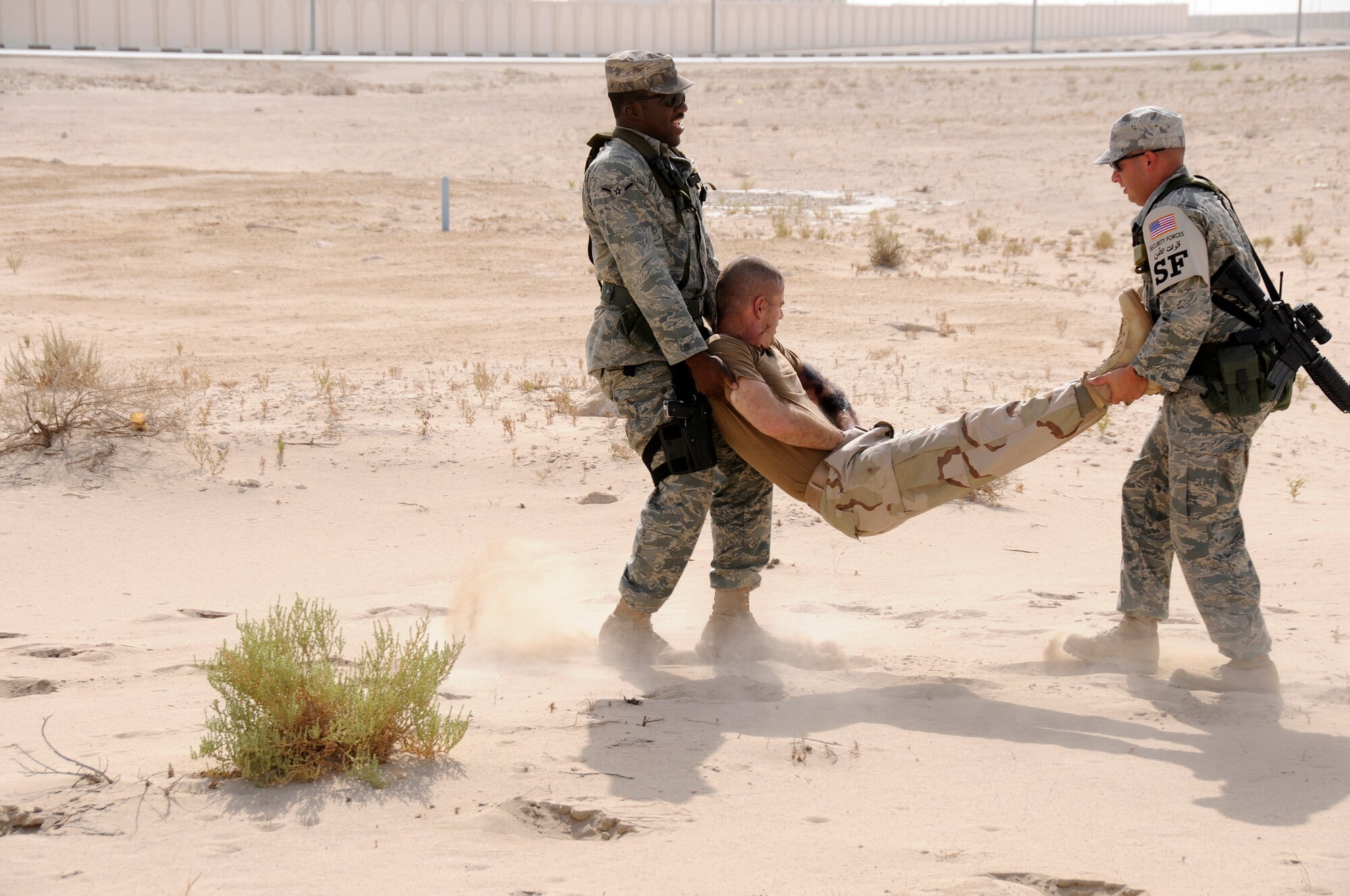 SOUTHWEST ASIA -- Airman Kenneth Perry at the head and Tech. Sgt. Chad Roberts, both from the 380th Expeditionary Security Forces Squadron, use the two man carry on a simulated burn victim to carry him out of harms way here Sept. 30. The victim is Capt. Kevin Eberhart from the 380th Air Expeditionary Wing. The 380th AEW exercise controllers have designed a variety of scenarios to aid in the wing's emergency preparedness. The exercises are designed to improve response times while following procedures. They are also enlisted to increase responders' knowledge of life-saving techniques and the ability to excel in the face of adversity. Amn Perry, deployed from the 325th SFS Tyndall Air Force Base, Fla., is from Atlanta, Ga. Sergeant Roberts is from Mansfield, Ohio, and deployed out of the 88th SFS Wright-Patterson AFB, Ohio. Capt. Eberhart's hometown is San Antonio, Texas. (U.S. Air Force photo/Tech. Sgt. Christopher A. Campbell)(released)  