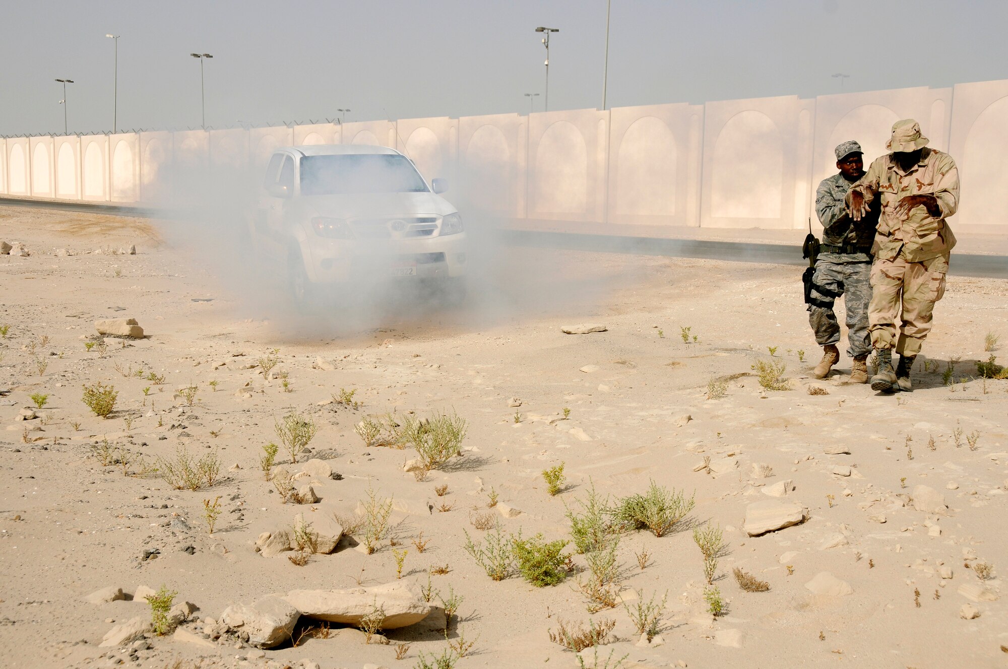 SOUTHWEST ASIA -- Airman Brent Banks from the 380th Expeditionary Security Forces Squadron renders aid to a simulated burn victim while a truck is on fire in the background here Sept. 30. The burn victim is Tech. Sgt. Curtis Cross from the 380th Air Expeditionary Wing. The base exercise controllers have designed a variety of scenarios to aid in the wing's emergency preparedness. The exercises are designed to improve response times while following procedures. They are also enlisted to increase responders' knowledge of life-saving techniques and the ability to excel in the face of adversity. Airman Banks, a native of Pensacola, Fla., is deployed from the 28th SFS Ellsworth Air Force Base, S.D. Sergeant Cross' hometown is Huntsville, Ala..(U.S. Air Force photo/Tech. Sgt. Christopher A. Campbell)(released)  