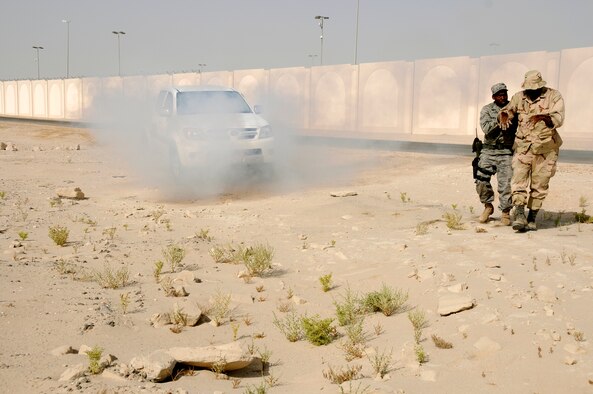SOUTHWEST ASIA -- Airman Brent Banks from the 380th Expeditionary Security Forces Squadron renders aid to a simulated burn victim while a truck is on fire in the background here Sept. 30. The burn victim is Tech. Sgt. Curtis Cross from the 380th Air Expeditionary Wing. The base exercise controllers have designed a variety of scenarios to aid in the wing's emergency preparedness. The exercises are designed to improve response times while following procedures. They are also enlisted to increase responders' knowledge of life-saving techniques and the ability to excel in the face of adversity. Airman Banks, a native of Pensacola, Fla., is deployed from the 28th SFS Ellsworth Air Force Base, S.D. Sergeant Cross' hometown is Huntsville, Ala..(U.S. Air Force photo/Tech. Sgt. Christopher A. Campbell)(released)  