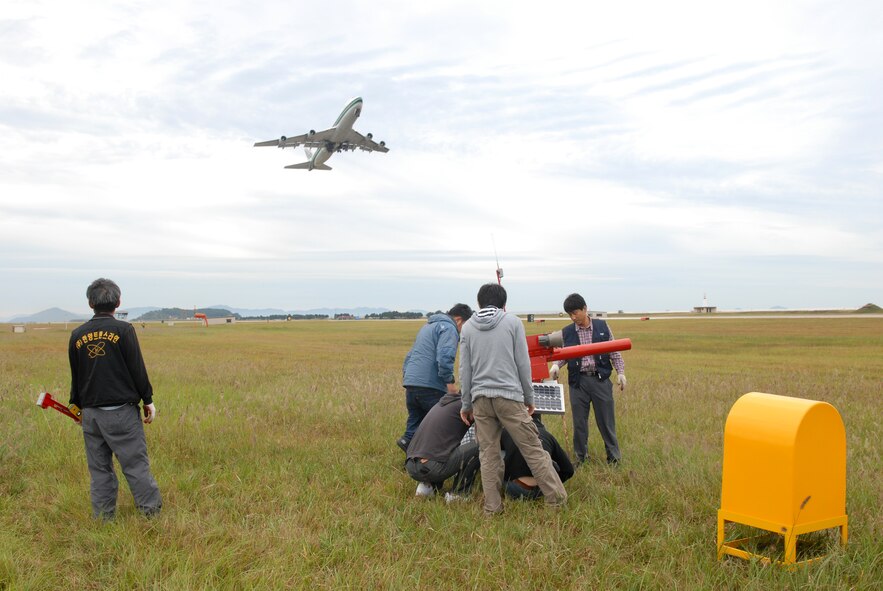 KUNSAN AIR BASE, Republic of Korea -- A member of a bird cannon installation crew watches an aircraft take off during a bird cannon installation here Sep. 29. The bird cannons are being installed as part of the Bird Wildlife Aircraft Strike Hazard program, which aims to keep the flight line and the variety of aircraft safe from bird hazards. The base shares its flight line with the Republic of Korea Air Forces' 8th Fighter Wing and Korean Airlines. (U.S. Air Force photo by Senior Airman Angela Ruiz)