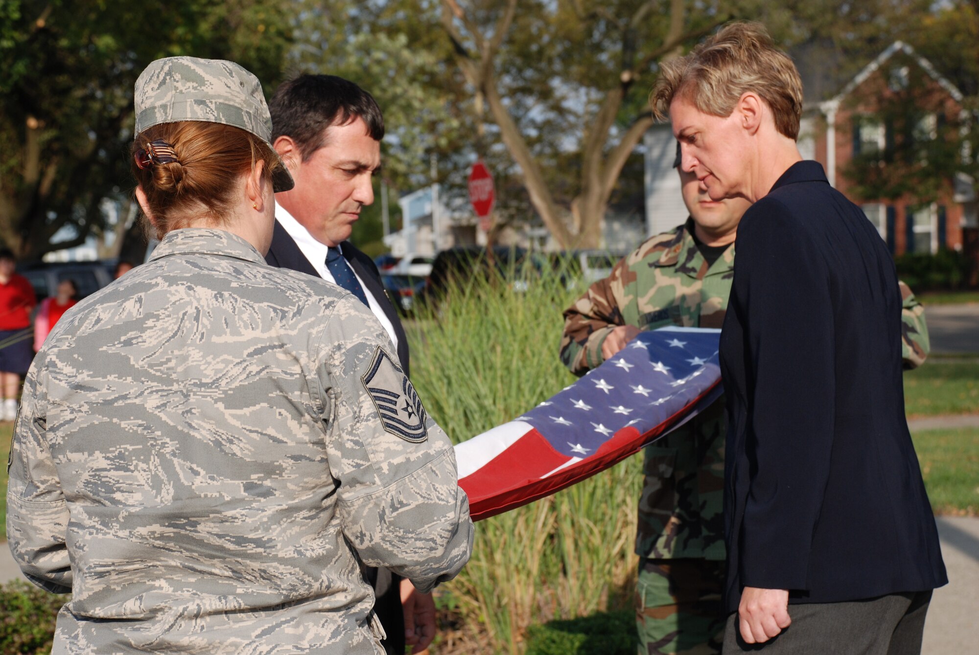 A four-member military-civilian flag detail folds the American flag during a retreat ceremony held September 30 at The Prairies at Wright Field military housing. Team members from left are Master Sergeant Julie A. Boyer, Dr. Nicholas J. DelRaso, Major Leamon K. Viveros (partially hidden) and Dr. Camilla A. Mauzy. (U.S. Air Force photo/Chris Gulliford)