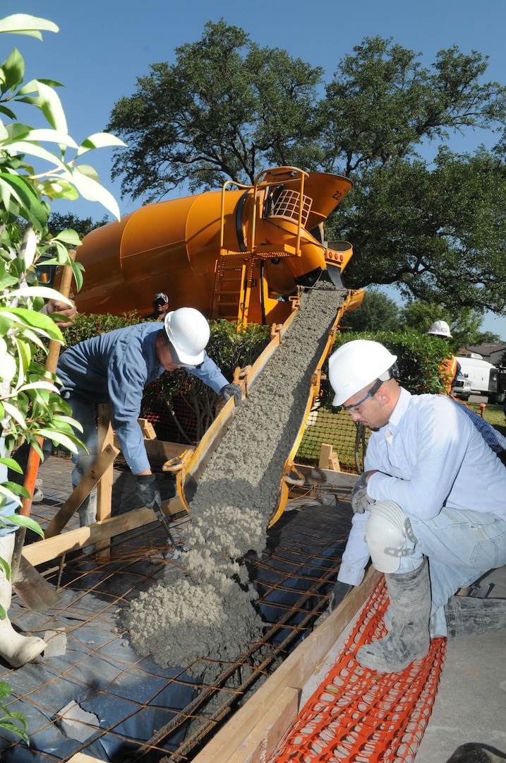 Juan (left) and Jesse Renteria, sub-contractors for Pinnacle/Hunt, pour concrete for a driveway in base housing Oct. 1. (U.S. Air Force photo by Rich McFadden)