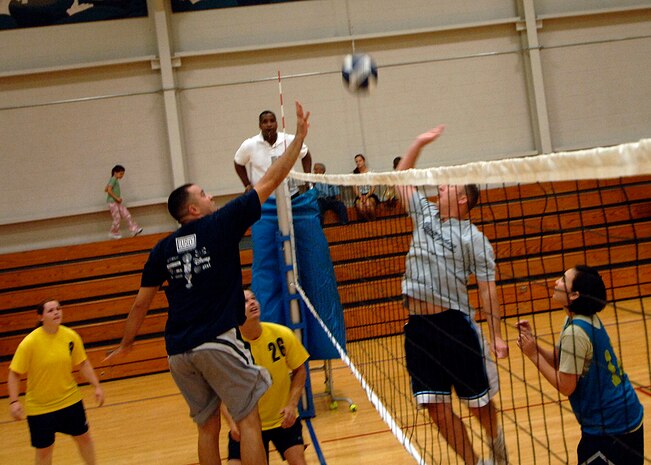 Orlando Rodriguez (left) and Chris Sinclair (right) jump towards the volley ball to spike at one another's side of the court at the base fitness center Sept. 30. Rodriguez is with the 437th Aerial port squadron and Sinclair is with the 437th Communications squadron. APS defeated COM 25-17 in two out of three games. (U.S. Air Force photo/Airman 1st Class Timothy Taylor)
