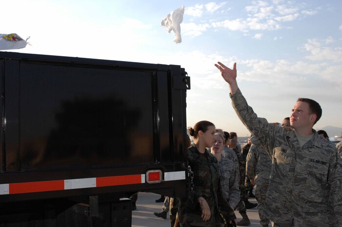 NELLIS AIR FORCE BASE, Nev. -- Airman Thomas Cole, 57th Component Maintenance Squadron, throws away his collected debris near the base runway during the 57th Wing foreign object debris (FOD) walk here on Sept. 30, 2008. FOD walks are conducted on a regular basis to prevent debris from potentially damaging Air Force aircraft assets. (U.S. Air Force Photo by/Senior Airman Larry E. Reid Jr.)