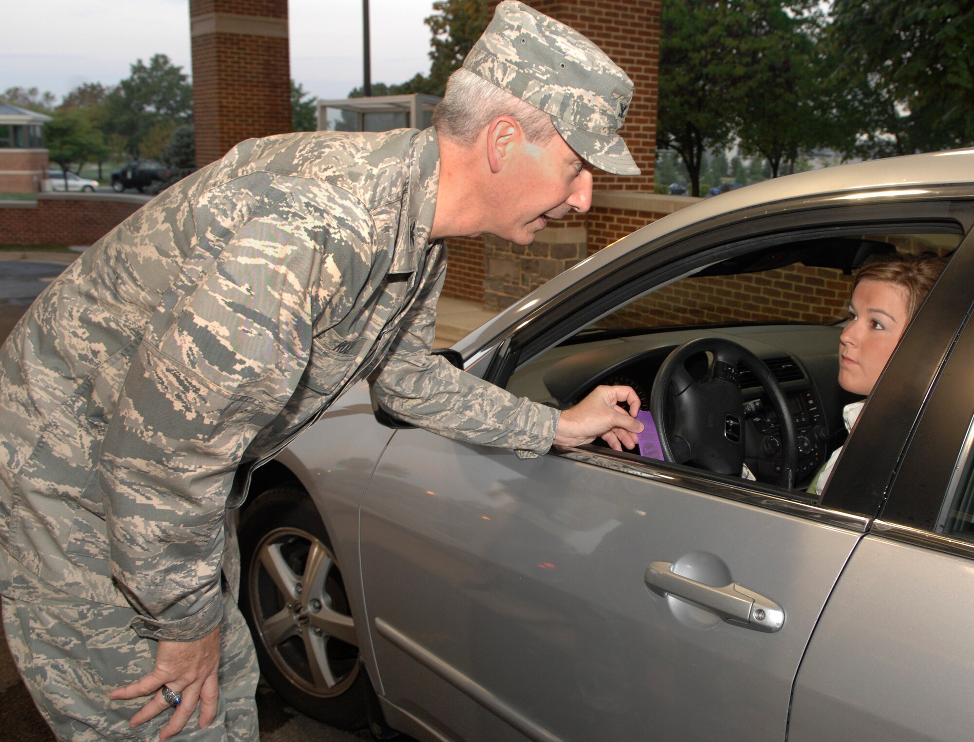 Col. Jon A. Roop, 11th Wing commander, hands out a purple ribbon to Amanda Watson, from the Defense Intelligence Agency, Oct. 1 at Bolling’s main gate, to help promote Domestic Violence Awareness Month.  October is Domestic Violence Awareness month. (U.S. Air Force photo by Senior Airman Tim Chacon)