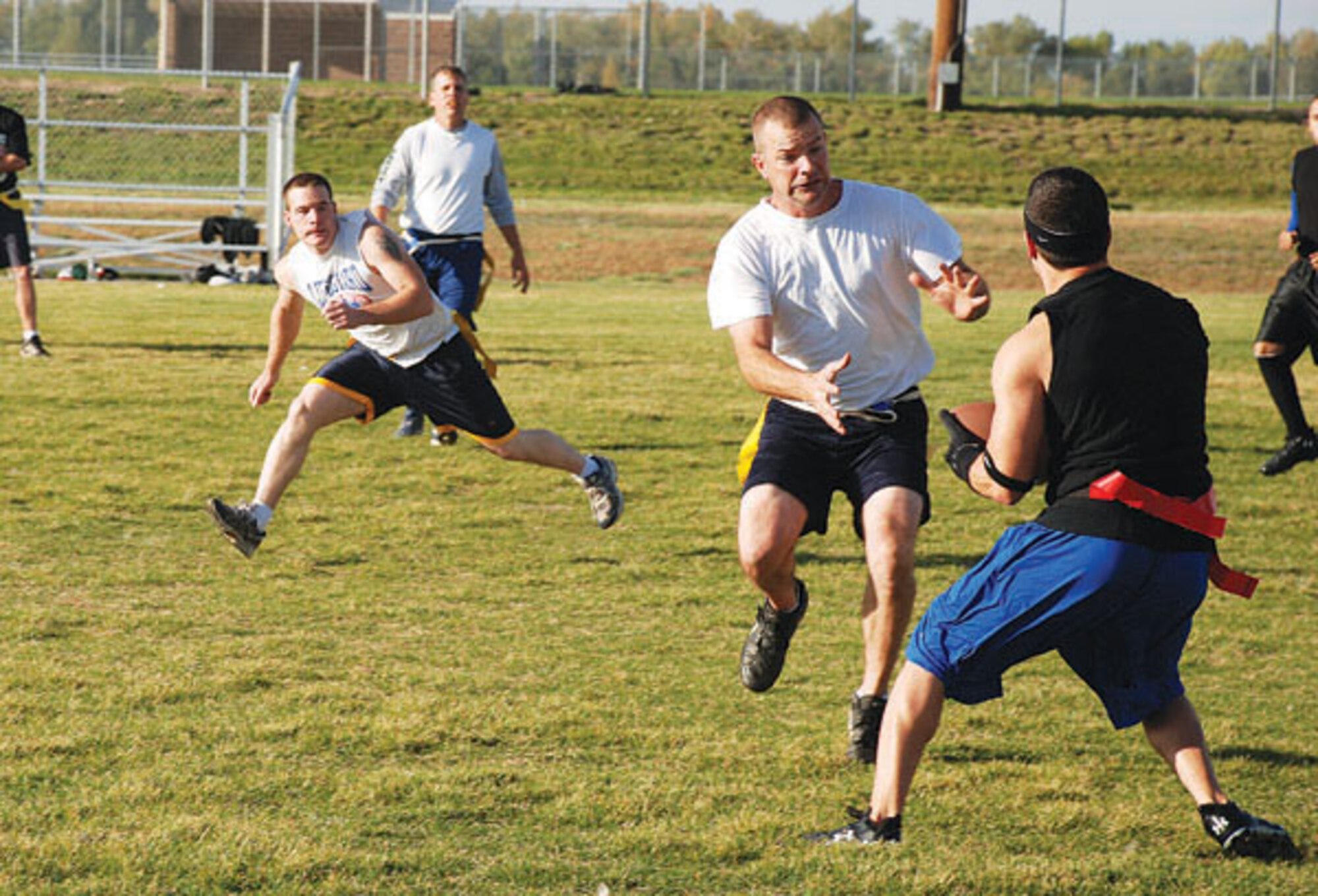 Gearold Crouse and Andrew Kose from the civil engineer team prepare to snatch the flags off the operations group's ball carrier. For flag football, instead of a tackle, the dangling flags count as the markers. (Photos by Airman 1st Class Daryl Knee)
