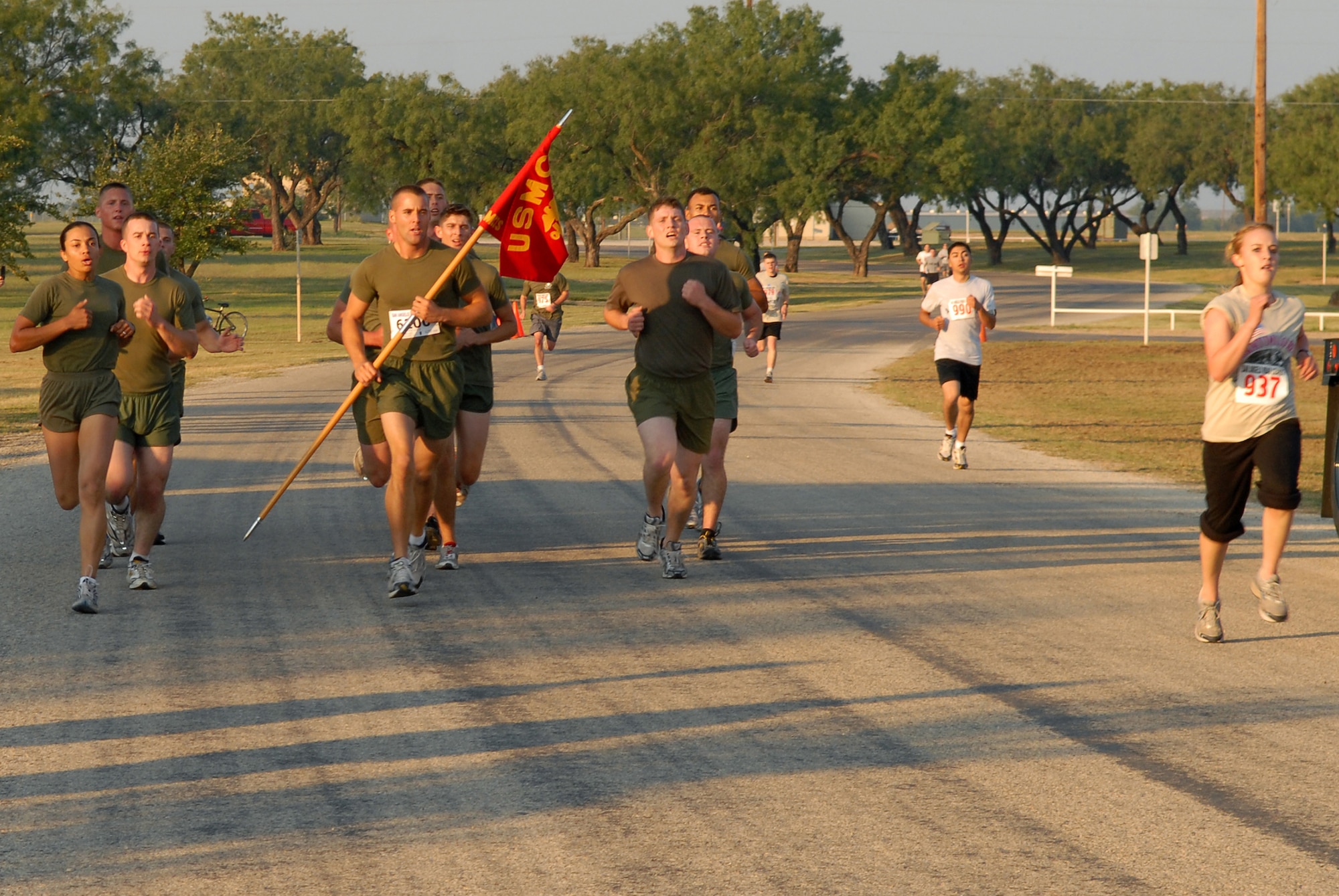 Members of the Marine Corps Detachment Goodfellow team (left) approach the finish line as the top finishers in the two-mile military formation race as Kelsey Koningsor (right) approaches the finish line as the top female finisher in the two-mile individual race portion of the 2008 ArmyDillo Run at Mary E. Lee Park in San Angelo, Texas, Sept. 27.  More than 350 people participated in the annual event, which benefits the Sentinel Foundation and consists of a 10-kilometer race, a two-mile individual race, a two-mile team race, and a two-mile military formation race.  The MARDET team won the formation race with a time of 13:04 while Koningsor came in with a time of 14:23:31.  (U.S. Air Force photo by Senior Airman Kasabyan Musal)