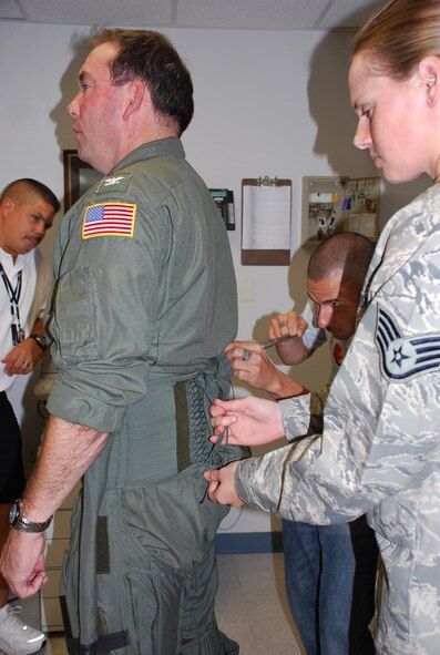 Recently, the Aircrew Life Support and Survival Equipment career fields merged into the new Air Force Specialty known as Aircrew Flight Equipment. (r to l) Staff Sgt. Sara Schiel instructs Staff Sgt. Travis Roman, on some of his new duties, such as the proper way to lace up an anti-G suit.   Capt. T.D. Smyers, Naval Air Station Joint Reserve Base Fort Worth installation commander, volunteered to assist in this training as he is prepared for his F-16 familiarization flight with the 457th Fighter Squadron Spads. (U.S. Air Force Photo/Tech. Sgt. Julie Briden-Garcia)