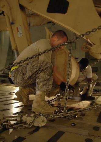 Airman 1st Class Donald Barnec secures a HMEE to the floor of a C-5 using hardened steel chains and clamps Sept. 29 on the Charleston AFB flightline. Airman Barnec is an air transportation journeyman with the 437th Aerial Port Squadron. Air transportation journeymen are responsible for ensuring all cargo is secured properly for takeoff.  (U.S. Air Force photo/Airman 1st Class Timothy Taylor)