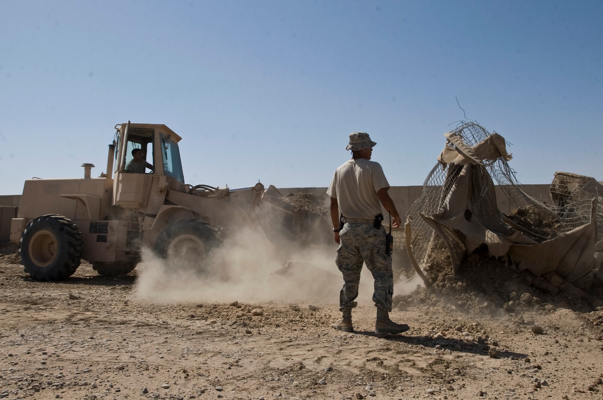 ALI BASE, Iraq -- Staff Sgt. Leonard Rodriguez spots Airman 1st Class Andrew Williamson, 407th Expeditionary Civil Engineer Squadron heavy equipment operators, as he tears down barricades Sept. 30, 2008. Airmen of the 407th ECES aided the force protection unit to move to a new location, along with tearing down remaining barricades. Rodriguez is deployed from Malmstrom Air Force Base, Mont. Williamson is deployed from F. E. Warren AFB, Wyo. (U.S. Air Force photo/Airman 1st Class Christopher Griffin)