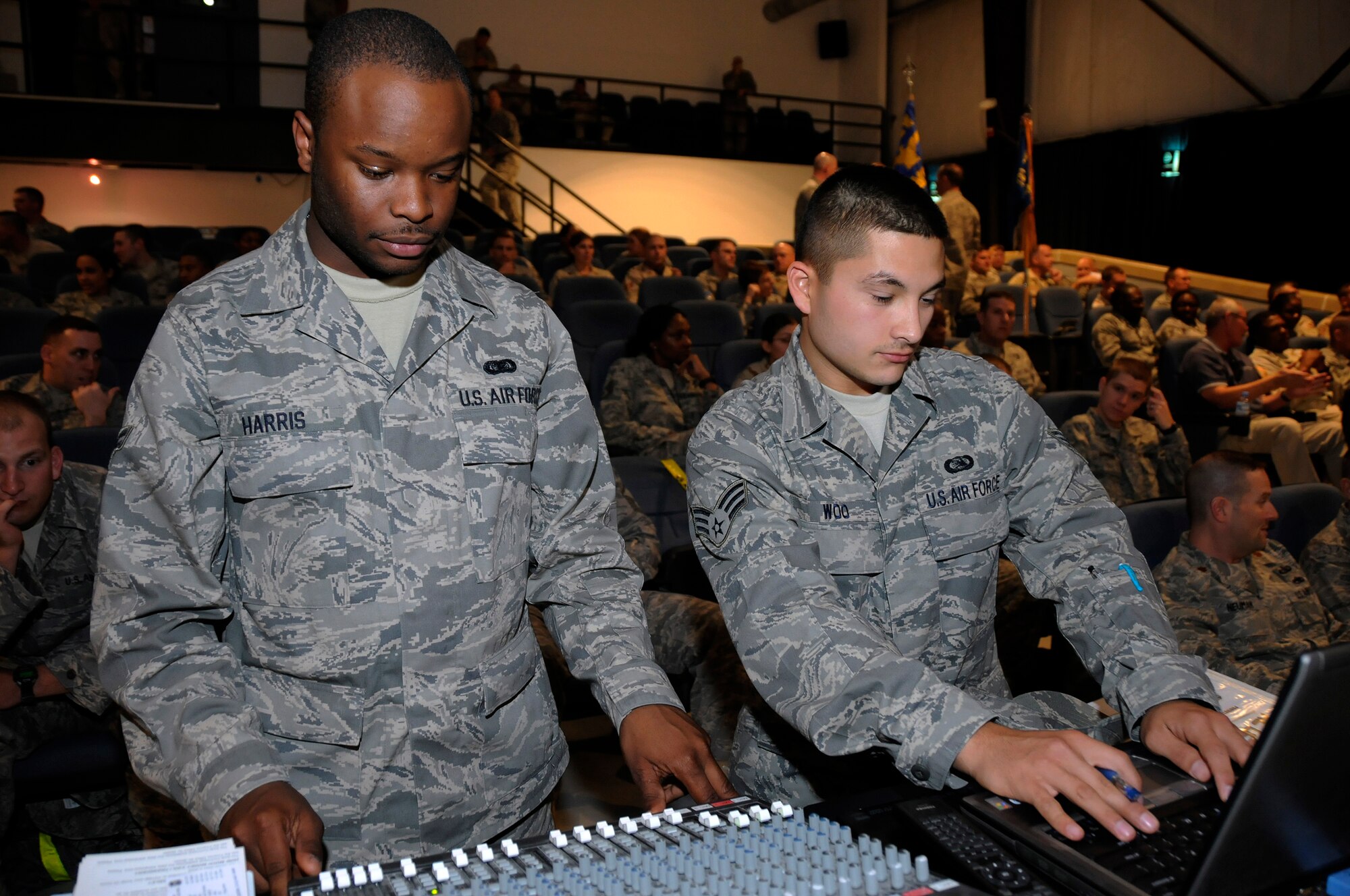 Airman 1st Class Quincy Harris and Senior Airman Bruce Woo, both assigned to the 379th Expeditionary Communications Squadron, provide audiovisual support for the base's monthly promotion and recognition ceremony Sept. 30, 2008.  Airman Harris works the sound board, while Airman Woo is in charge of the slide show and visuals.  Airman Harris, a native of Columbus, Mo., is deployed from Keesler Air Force Base, Miss.  Airman Woo, hailing from Canton, Ohio, is deployed from Kadena Air Base, Japan.  Both are deployed to this undisclosed air base in Southwest Asia in support of Operations Iraqi and Enduring Freedom and Joint Task Force-Horn of Africa.  (U.S. Air Force photo by Tech. Sgt. Michael Boquette/Released)