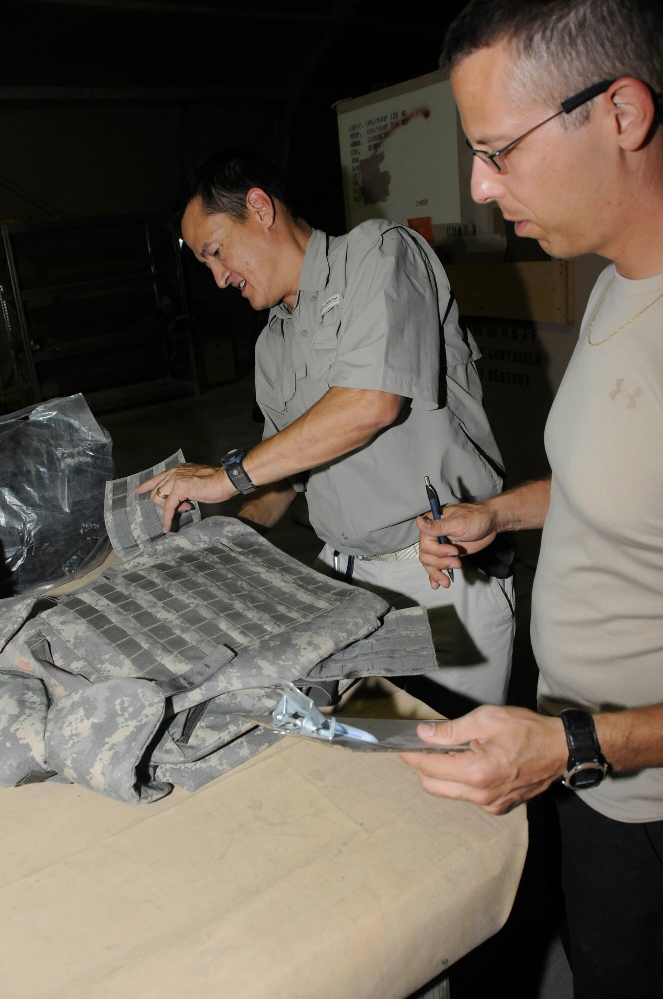 Mr. Ron Lee, logistical representative assigned to the Combined Air and Space Operations Center, conducts an inspection of combat protective gear while Mr. Jim McGreevy, also assigned to the CAOC, writes down any defects and the identifying information on an inventory sheet Sept. 29, 2008, at an undisclosed air base in Southwest Asia.  Mr. Lee, a native of Columbia, Md., is deployed from Fort Meade, Md., and Mr. McGreevy, a native of Fort Meade, Md., is deployed from Fort Meade, Md.  Both are deployed supporting Operations Iraqi and Enduring Freedom and Joint Task Force-Horn of Africa. (U.S. Air Force photo by Staff Sgt. Darnell T. Cannady)