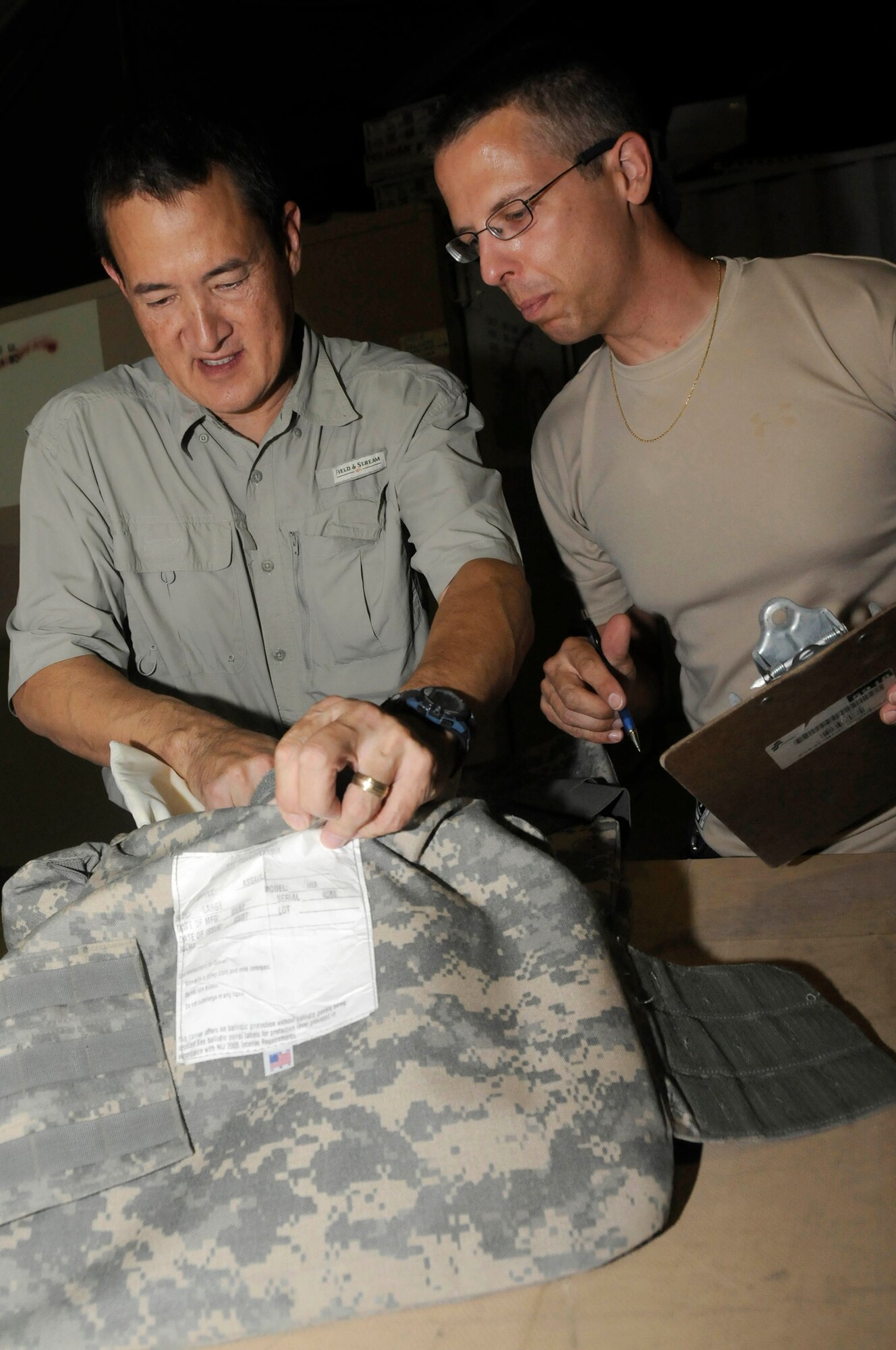 Mr. Ron Lee, logistical representative assigned to the Combined Air and Space Operations Center, conducts an inspection of combat protective gear while Mr. Jim McGreevy, also assigned to the CAOC, writes down any defects and the identifying information on an inventory sheet Sept. 29, 2008, at an undisclosed air base in Southwest Asia.  Mr. Lee, a native of Columbia, Md., is deployed from Fort Meade, Md., and Mr. McGreevy, a native of Fort Meade, Md., is deployed from Fort Meade, Md.  Both are deployed supporting Operations Iraqi and Enduring Freedom and Joint Task Force-Horn of Africa. (U.S. Air Force photo by Staff Sgt. Darnell T. Cannady)