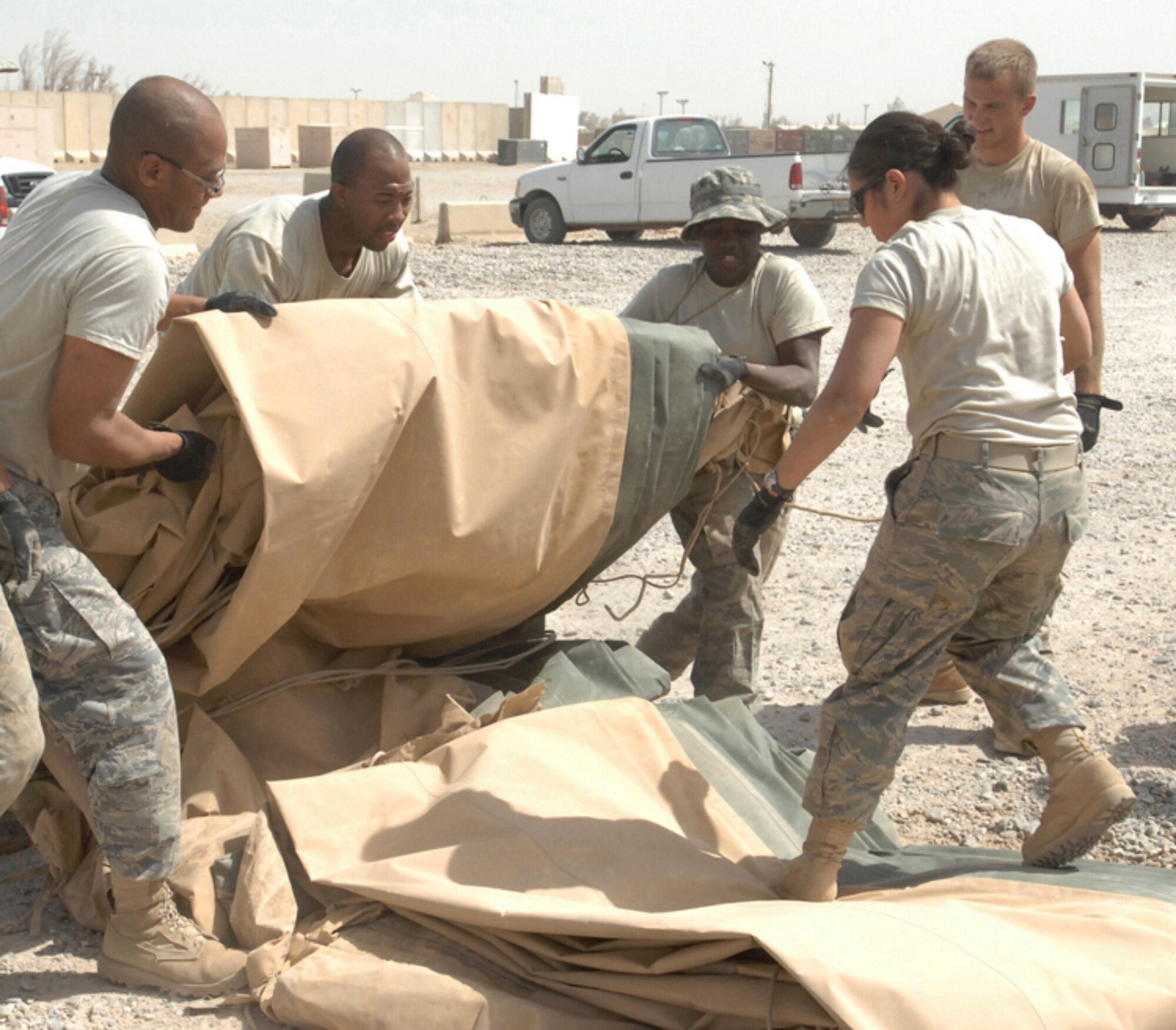 ALI BASE, Iraq -- Members from the 407th Expeditionary Civil Engineer and 407th Expeditionary Security Forces Force Protection Squadron fold the outer liner to the California shelter. They and other Airman packed it up for proper storage in its fiberglass shipping container. Shelter was previously used by the 407th ESFS Force Protection. (U.S. Air Force photo/Senior Master Sgt. Russell Dodson)