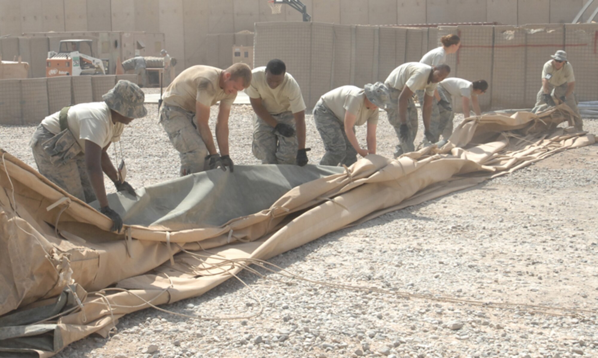 ALI BASE, Iraq -- Members from the 407th Expeditionary Civil Engineer and 407th Expeditionary Security Forces Force Protection Squadron fold the outer liner to the California shelter. They and other Airman packed it up for proper storage in its fiberglass shipping container. Shelter was previously used by the 407th ESFS Force Protection. (U.S. Air Force photo/Senior Master Sgt. Russell Dodson)