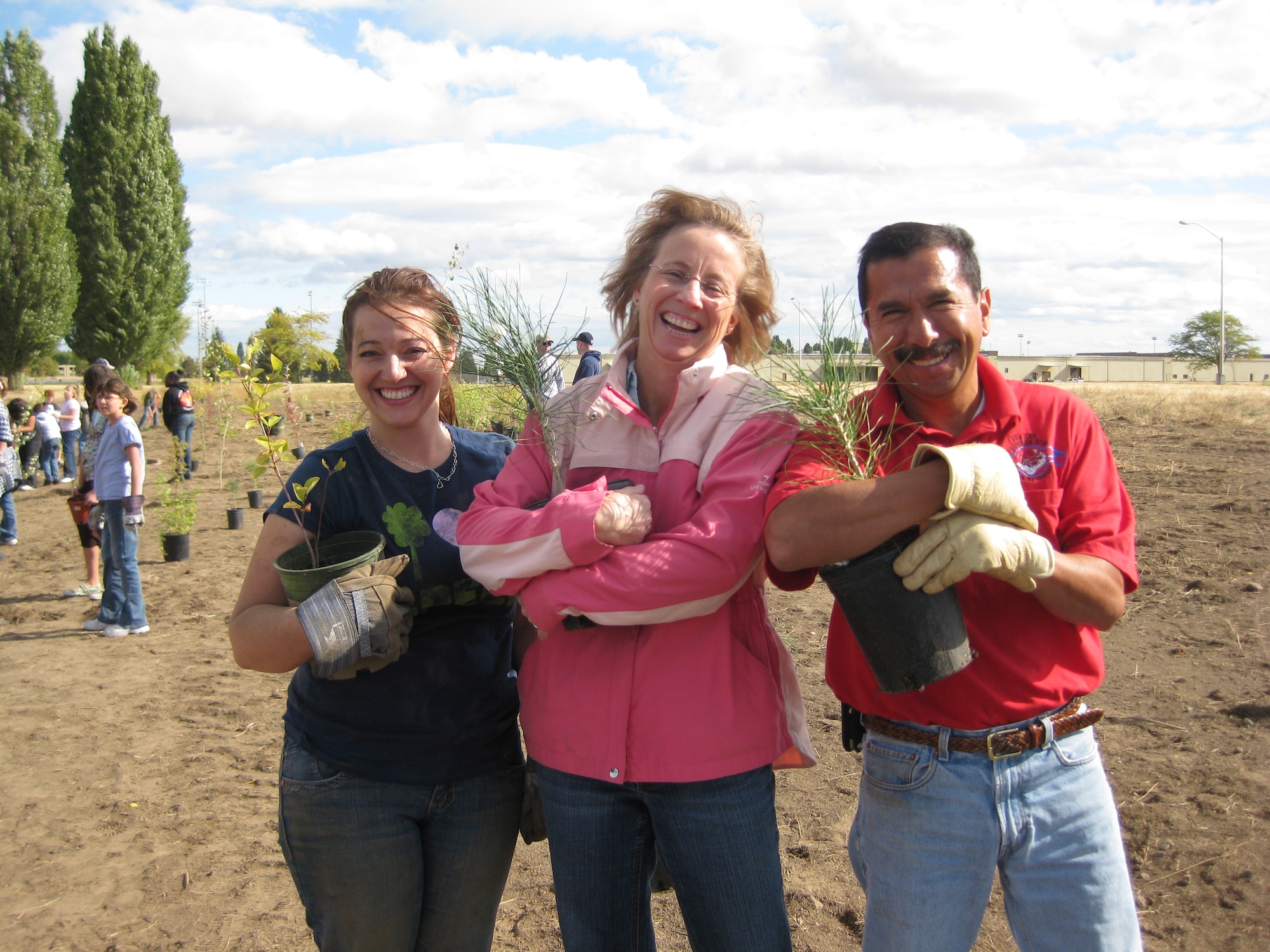 FAIRCHILD AIR FORCE BASE, Wash. – Three eager participants, Tami Calhoun, Diane Wulf and Joel Espinoza from the 92nd Civil Engineer Squadron Environmental Flight are seen clutching their treasures (ponderosa pine and common snowberry) to be planted in support of National Public Lands Day.  These volunteers graciously assisted the children from Michael Anderson Elementary in planting numerous native trees and shrubs Sept 25. (U.S. Air Force photo / Mary Farver)