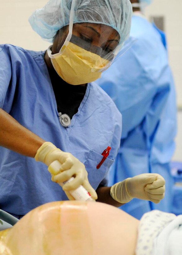 Second Lt. Chanel N. Mitchell, 779th Medical Group nurse, cleans the abdomen of Mrs. McCoy, Public Affairs Specialist for Naval Sea Systems Command in Washington D.C., before her scheduled C-section at the Maternal Child Unit of Malcolm Grow Medical Center. (USAF photo by Tech. Sgt. Suzanne M. Day)