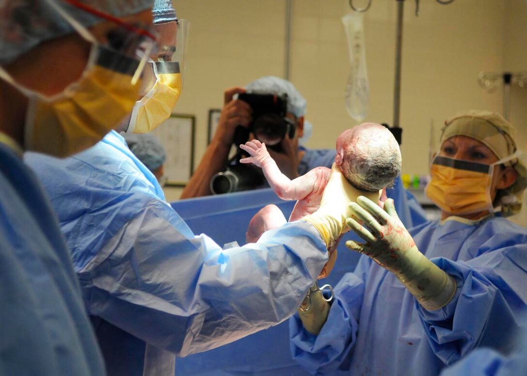 Captain Paul H. Bornemann, 779th Medical Group resident, assists Capt. Stephanie Wright, 779th Medical Group physician, with the delivery of Jae Riley McCoy at the Maternal Child Unit of Malcolm Grow Medical Center. (USAF photo by Tech. Sgt. Suzanne M. Day)