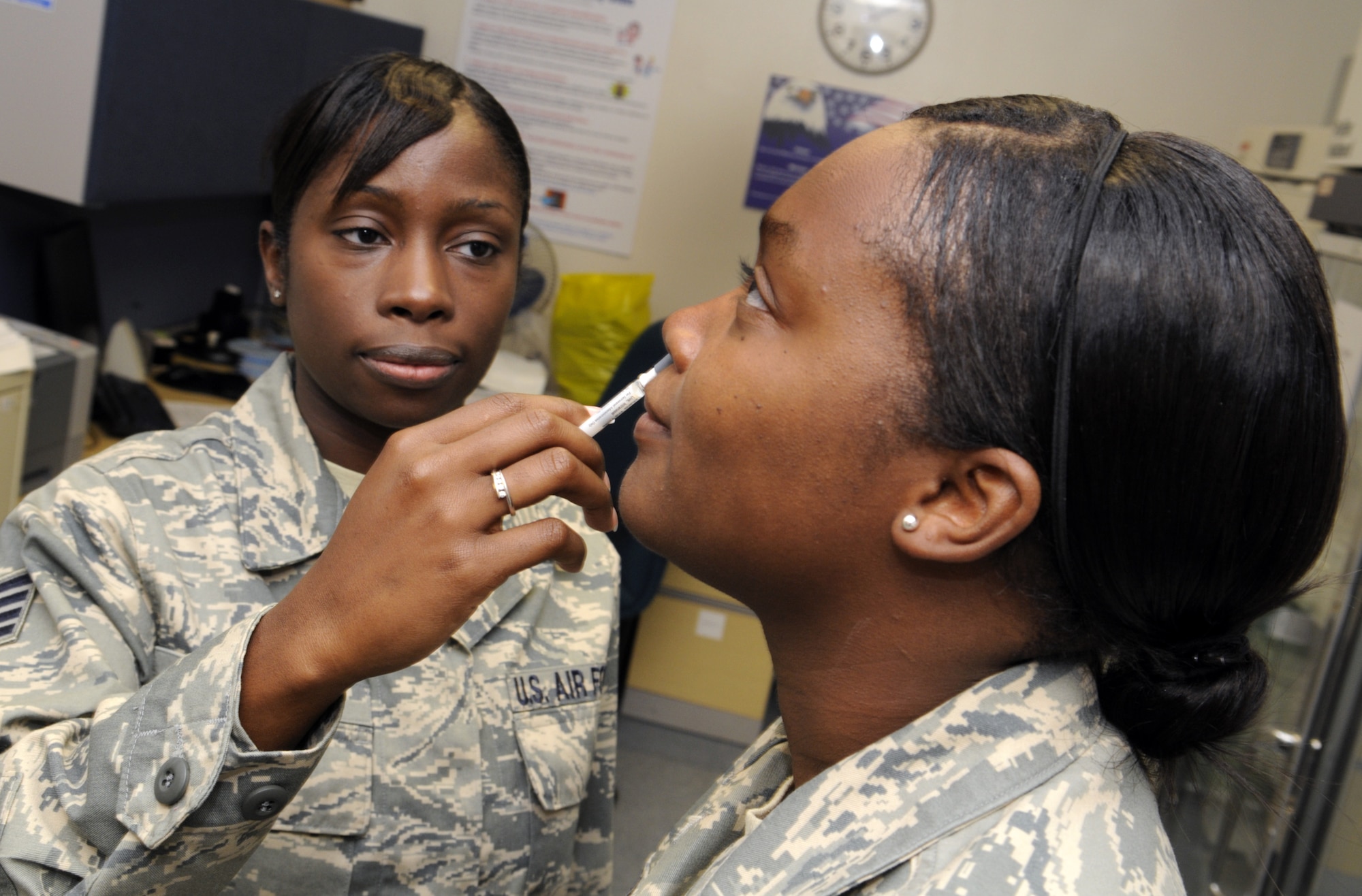 SSgt. Natasha Walker administers the flu mist to SrA Natasha Lomax at Robins clinic. U. S. Air Force photo by Sue Sapp