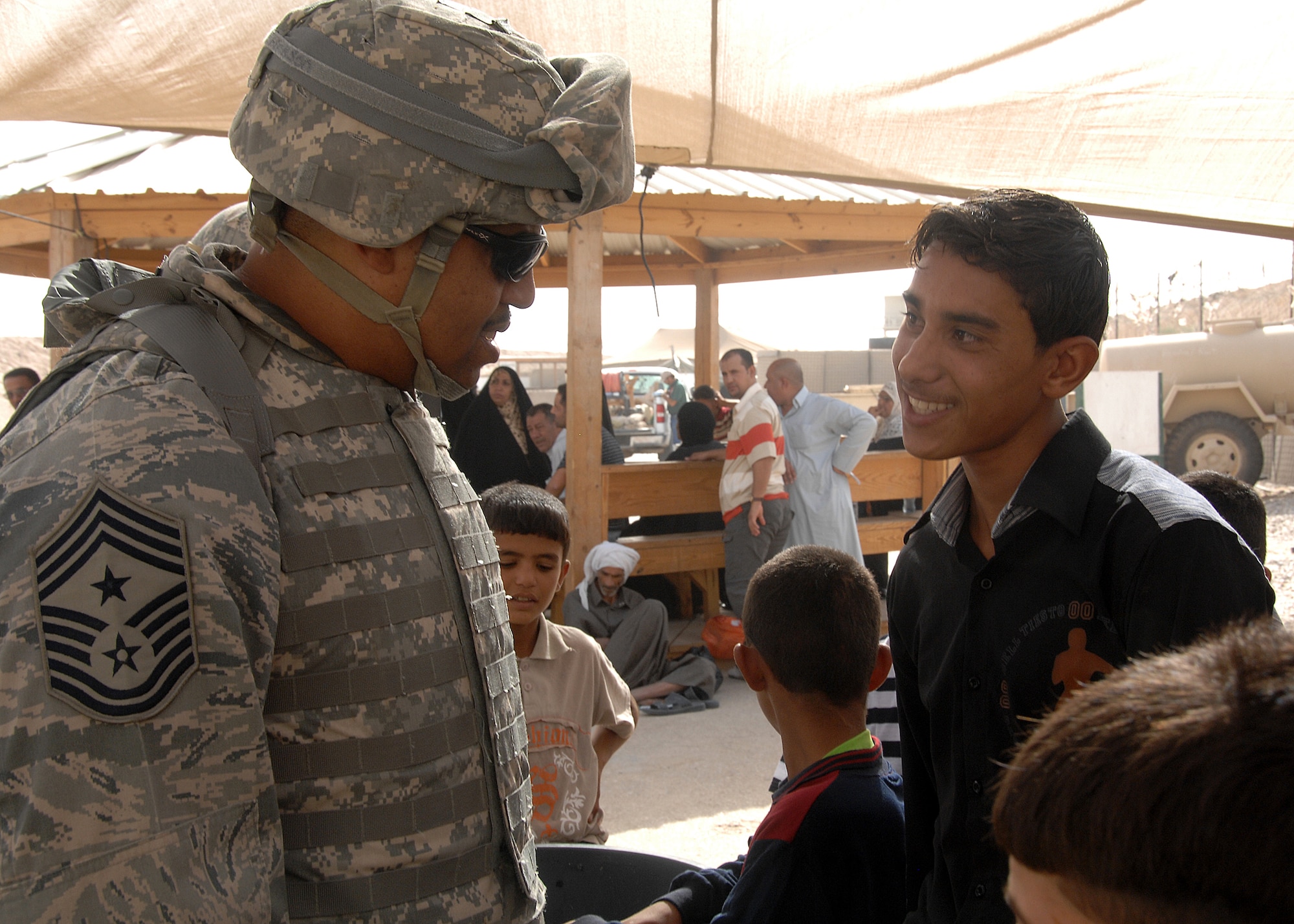 Camp Bucca, Iraq -- Chief Master Sgt. Jeffrey Antwine, 386th Air Expeditionary Wing command chief, jokes with a young Iraqi boy waiting to visit his father at the Theater Internment Facility (TIF) at Camp Bucca, Iraq, on Sept. 29. The 887th Expeditionary Security Forces Squadron controls access to detainees at the TIF and processes visitation procedures for family members. The Air Force works side by side with Army Soldiers in manning the facility, which houses more than 18,000 detainees. (U.S. Air Force photo/Tech. Sgt. Raheem Moore)
