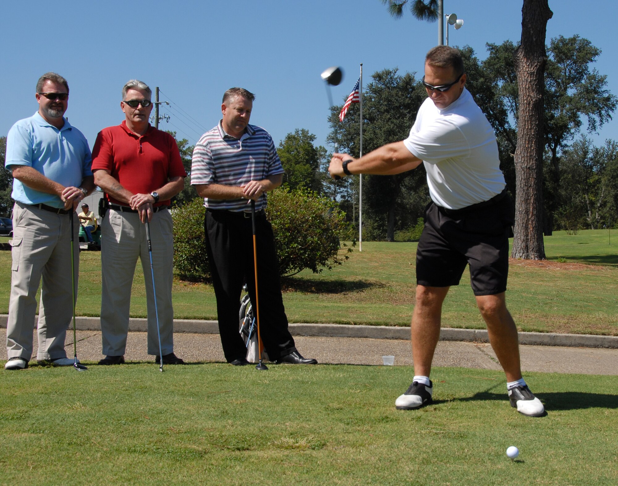 Senior Master Sgt. Roger Bloor "swings away" at the first hole of the Eglin Golf Course as members of the 53d Wing intramural golf-team watches.  The 53d WG team won the base championship this year in a match against the Air Force Research Lab team at Wind Swept Dunes in Freeport, Fla.  The match was tied after 18 holes, but the 53d WG took the win on the first hole of sudden death.  The team was unbeaten during the regular season and in the playoffs.  From left to right:  Rick Houchens, Chuck McBay, Tom Finnegan, Roger Bloor.  Photo by Staff Sgt. Samuel King Jr. 