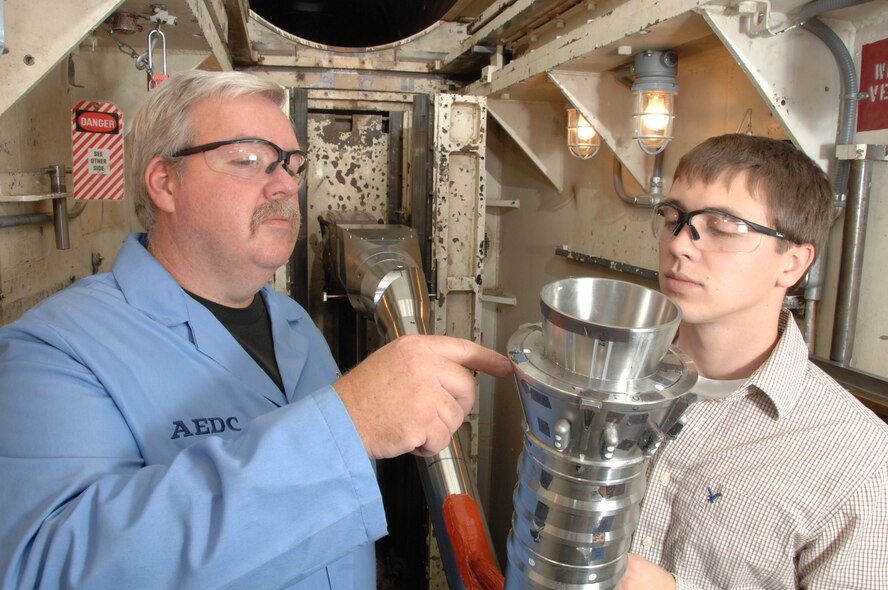From left, Joe Syler, Aerospace Testing Alliance outside machinist, inspects the Ares I first stage booster model in the center’s von Karman Facility’s Tunnel B while Jonathan Kodman, ATA test engineer on the project, looks on. (Photo by David Housch)