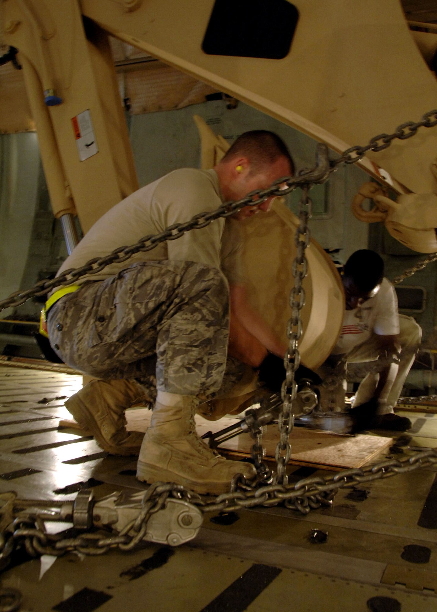 Airman 1st Class Donald Barnec secures Army High Mobility Engineer Excavator to the floor of a C-5 Galaxy Sept. 29 at Charleston Air Force Base, S.C. Airman Barnec is an air transportation journeyman with the 437th Aerial Port Squadron. Air transportation journeymen are responsible for ensuring all cargo is secured properly for takeoff. (U.S. Air Force photo/Airman 1st Class Timothy Taylor)
