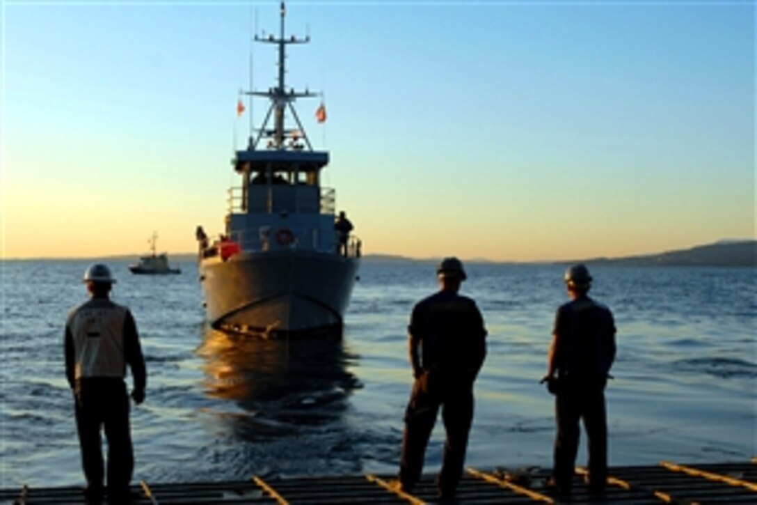 Sailors on the stern gate of the amphibious dock landing ship USS Rushmore await the arrival of a small craft during an early morning passenger transfer, Nanoose Firing Range, British Columbia, Sept. 28, 2008. Rushmore is supporting anti-submarine warfare training at the Nanoose firing range.