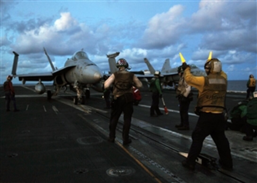 U.S. Navy Aviation Boatswain's Mate 3rd Class Robert Stuns directs an F/A-18C Hornet assigned to Strike Fighter Squadron 34 onto the number 3 steam-powered catapult as the sun sets on the flight deck of the USS Abraham Lincoln (CVN 72) on Sept. 6, 2008.  The Lincoln Strike Group is on deployment in the U.S. 7th Fleet area of responsibility.  
