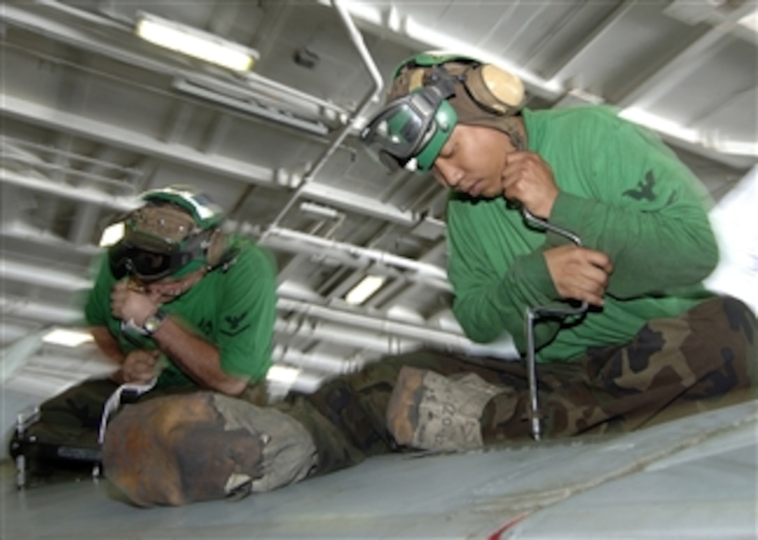 U.S. Navy Petty Officer 2nd Class Custer Peralta and Petty Officer 3rd Class Gabriele Hathaway unscrew wing panels on an F/A-18C Hornet aircraft aboard the aircraft carrier USS George Washington (CVN 73) in the Pacific Ocean on Aug. 25, 2008.  The George Washington is conducting training in the eastern Pacific Ocean before continuing to Commander Fleet Activities Yokosuka, Japan, where the ship will replace the aircraft carrier USS Kitty Hawk (CV 63) as the U.S. Navy's only forward-deployed aircraft carrier.  