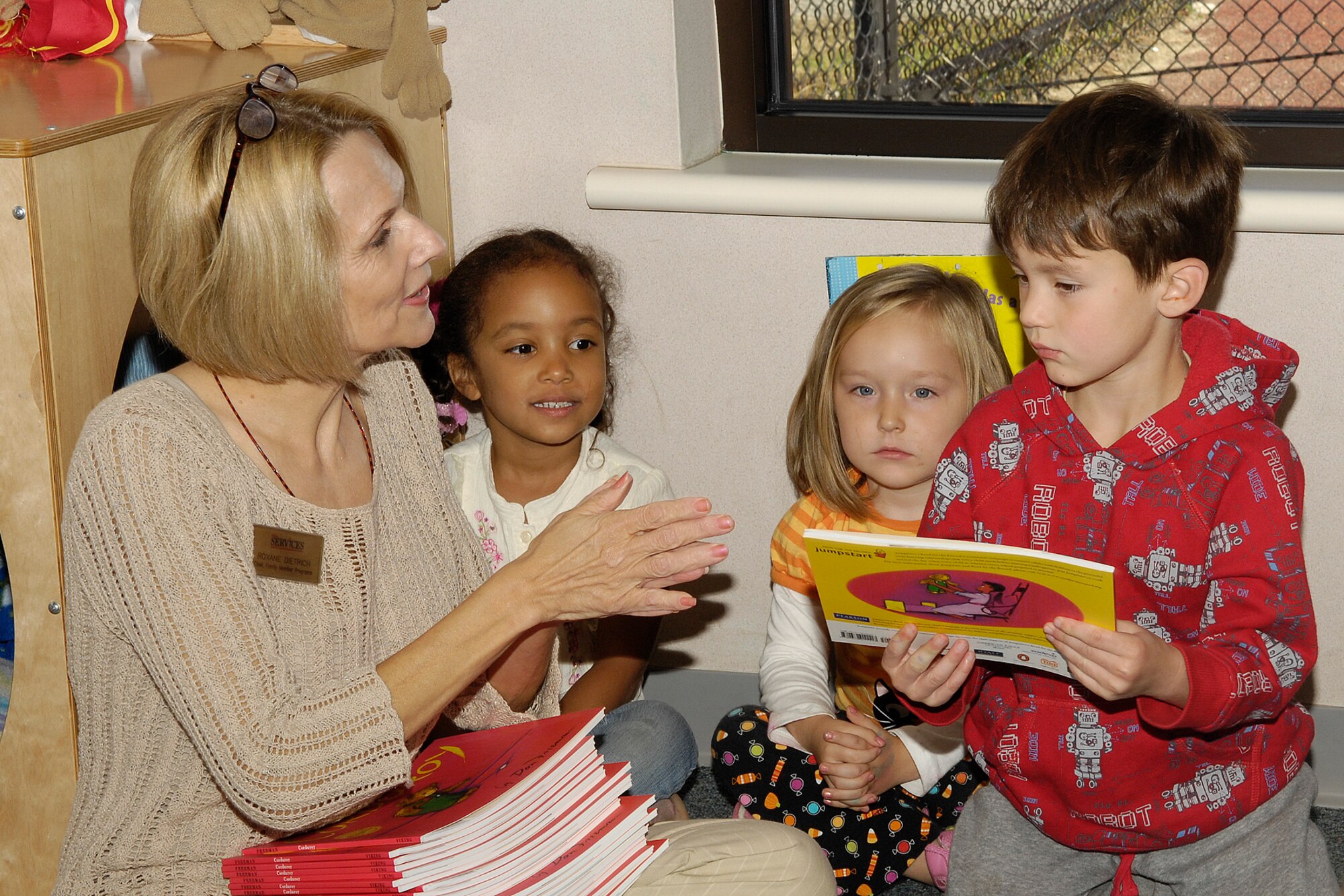 HANSCOM AFB, Mass. – Roxane Dietrich, Family Member Programs Flight chief, hands out copies of the book Corduroy to children in Room 9 at the Child Development Center on Oct. 2, as part of Jumpstart’s national Read for the Record campaign. The campaign is designed to bring attention to the importance of early education by encouraging hundreds of thousands of children and adults to read the same book on the same day. USO New England donated copies of the book Corduroy to children enrolled in the CDC’s pre-school program as part of the Read for the Record campaign. (U.S. Air Force photo by Linda LaBonte Britt)