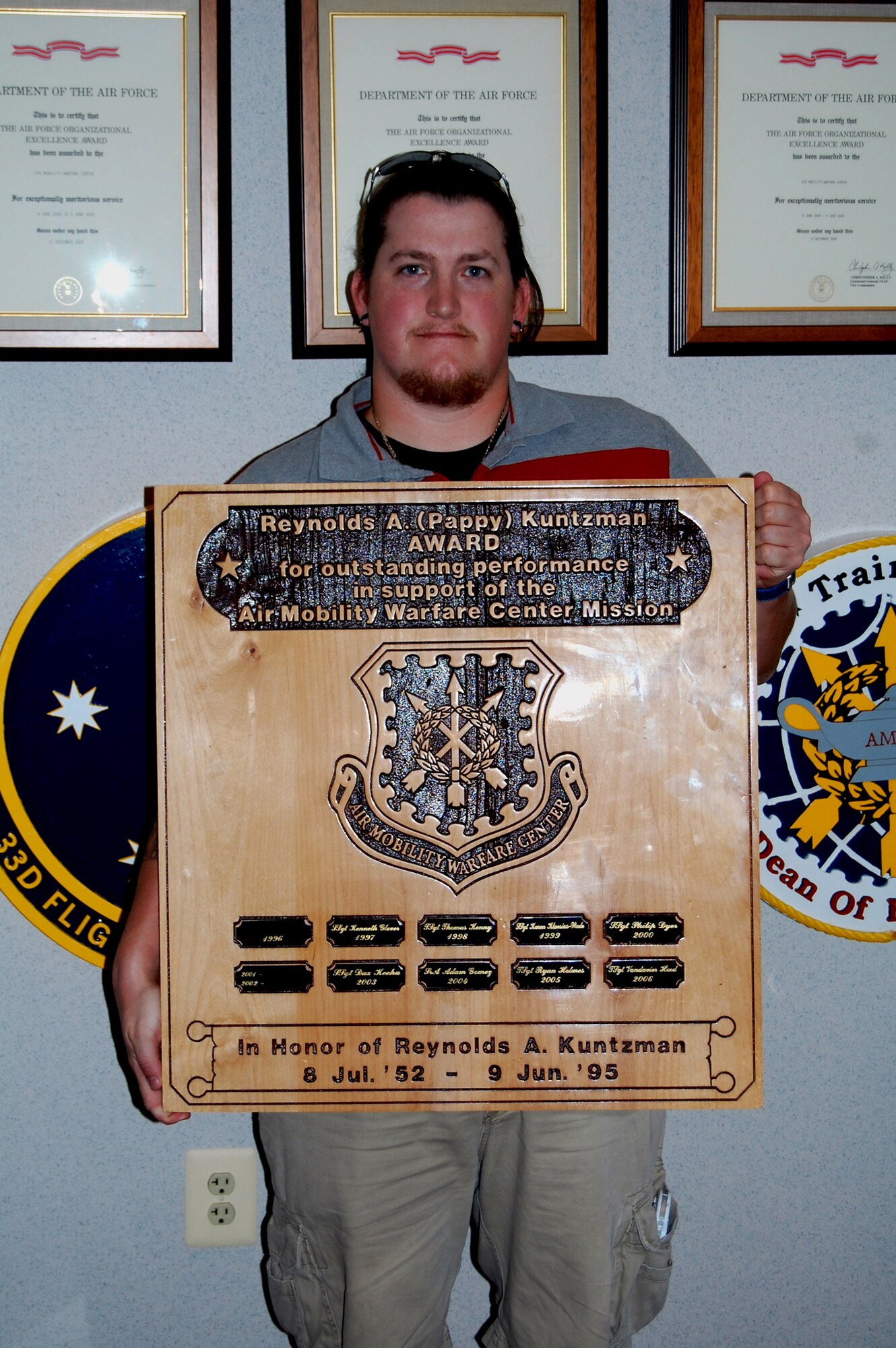 Jeremy Kuntzman, 29, from Manasass, Va., holds the plaque bearing his father's name, former Tech. Sgt. Reynolds A. Kuntzman, during a visit to the U.S. Air Force Expeditionary Center Aug. 21, 2008.  Sergeant Kuntzman died on June 9, 1995, while assigned to the center with the 421st Ground Combat Readiness Squadron.  After his death, the center's leadership created the Reynolds A. Kuntzman Duty performance award given annually to an Airman in the grades of E-1 through E-6 recognizing superior duty performance in support of the center's mission and community.  (U.S. Air Force Photo/Tech. Sgt. Scott T. Sturkol)