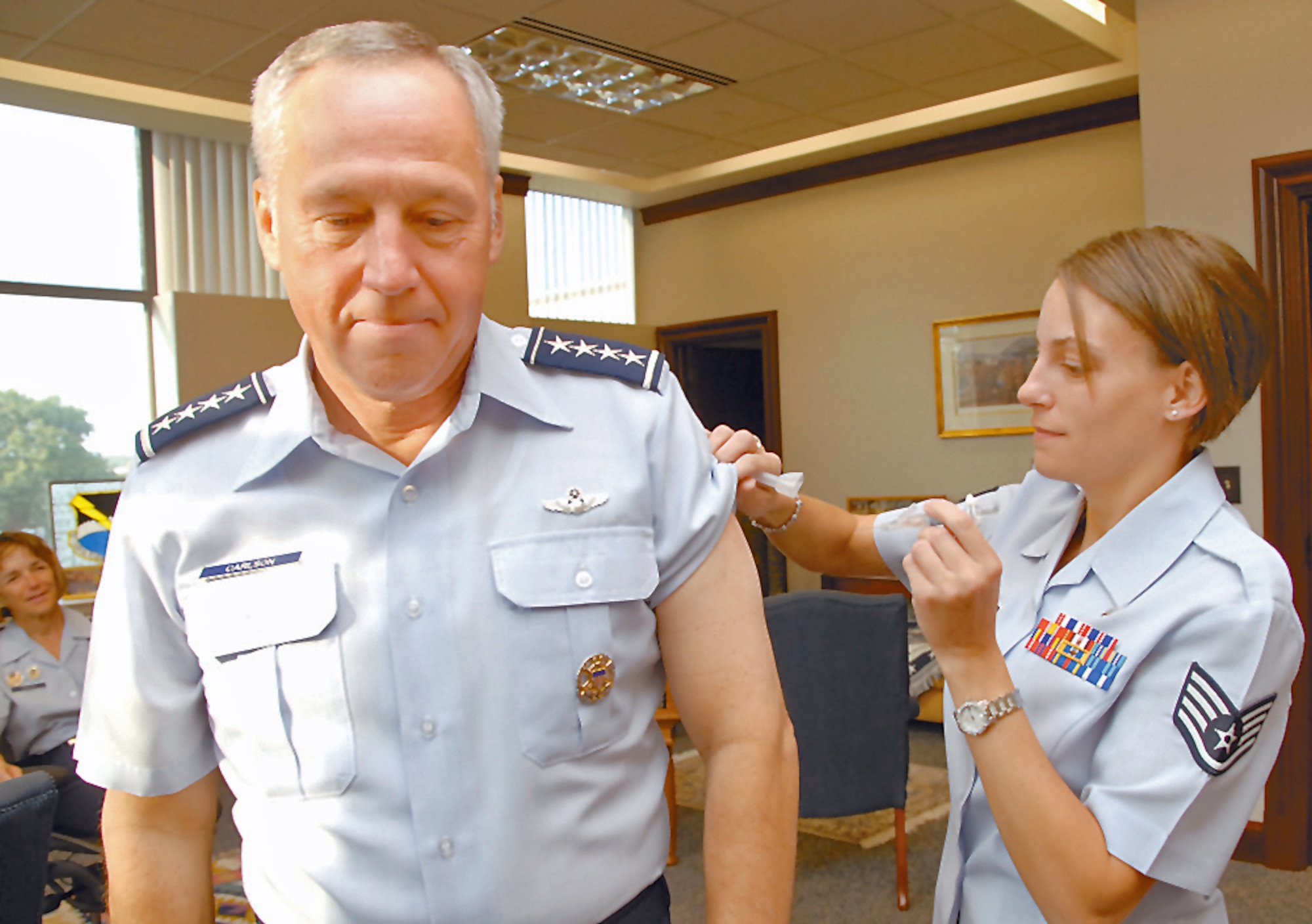 Gen. Bruce Carlson, Air Force Materiel Command commander, gets an annual flu shot from Staff Sgt. Amy Pelland of the 88th Medical Group, Wright-Patterson Medical Center.  With the influenza season rapidly approaching, medical experts recommend active duty Airmen and high-risk individuals receive either intranasal or injectable forms of the flu vaccine. (Skywrighter photo/Christy Webb)