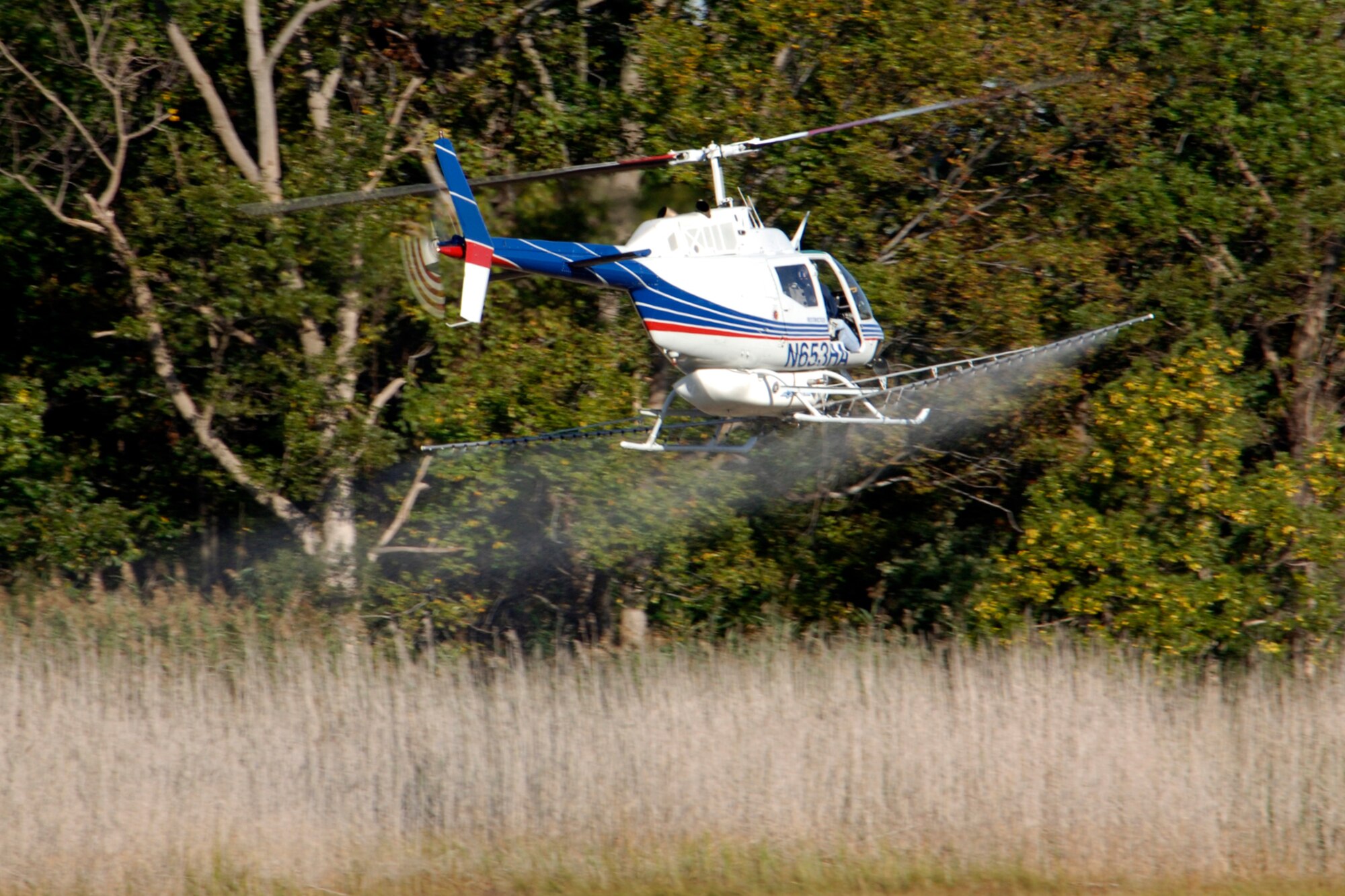 LANGLEY AIR FORCE BASE, Va. -- Brian Redding, a subcontracted pilot, flies a Bell OH 58B helicopter Oct. 2. The helicopter is outfitted with an aerial spray rig in order to spray and kill phragmites. Phragmites are a weed commonly found in marshes that grow fast and can overcome other plants in the area. (U.S. Air Force Photo/Airman 1st Class Jonathan Koob)