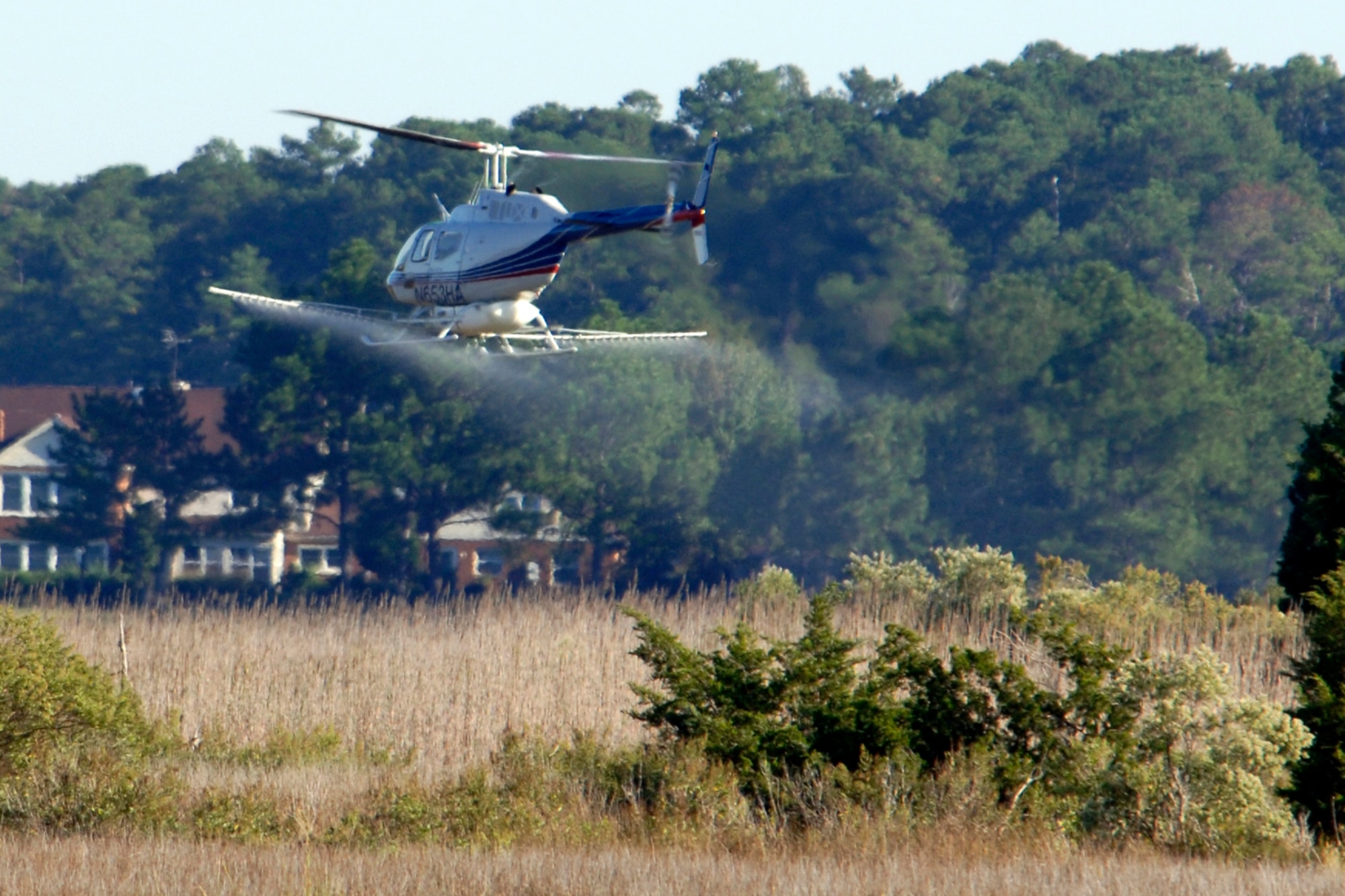 LANGLEY AIR FORCE BASE, Va. -- Brian Redding, a subcontracted pilot, flies a Bell OH 58B helicopter Oct. 2. The helicopter is outfitted with an aerial spray rig in order to spray and kill phragmites. Phragmites are a weed commonly found in marshes that grow fast and can overcome other plants in the area. (U.S. Air Force Photo/Airman 1st Class Jonathan Koob)