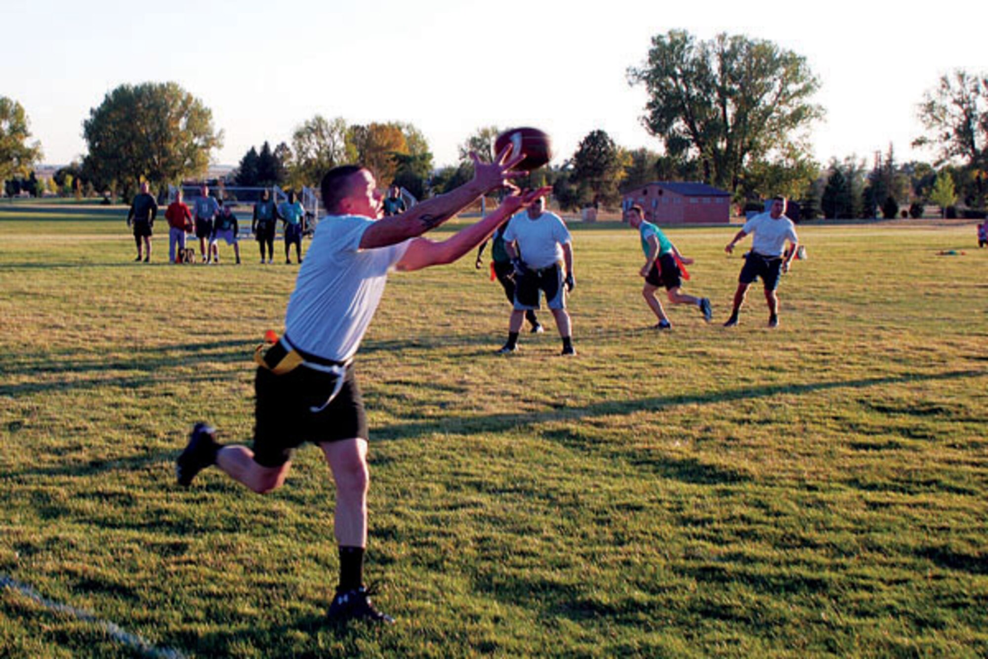 Amid shouts from the sideline, the 90th Civil Engineer Squadron’s quarterback Dan Conrad throws the football to Shaun Manard at the 90th CES and 790th Missile Security Forces Squadron game at the base football field Tuesday. (Photo by Airman 1st Class Daryl Knee)
