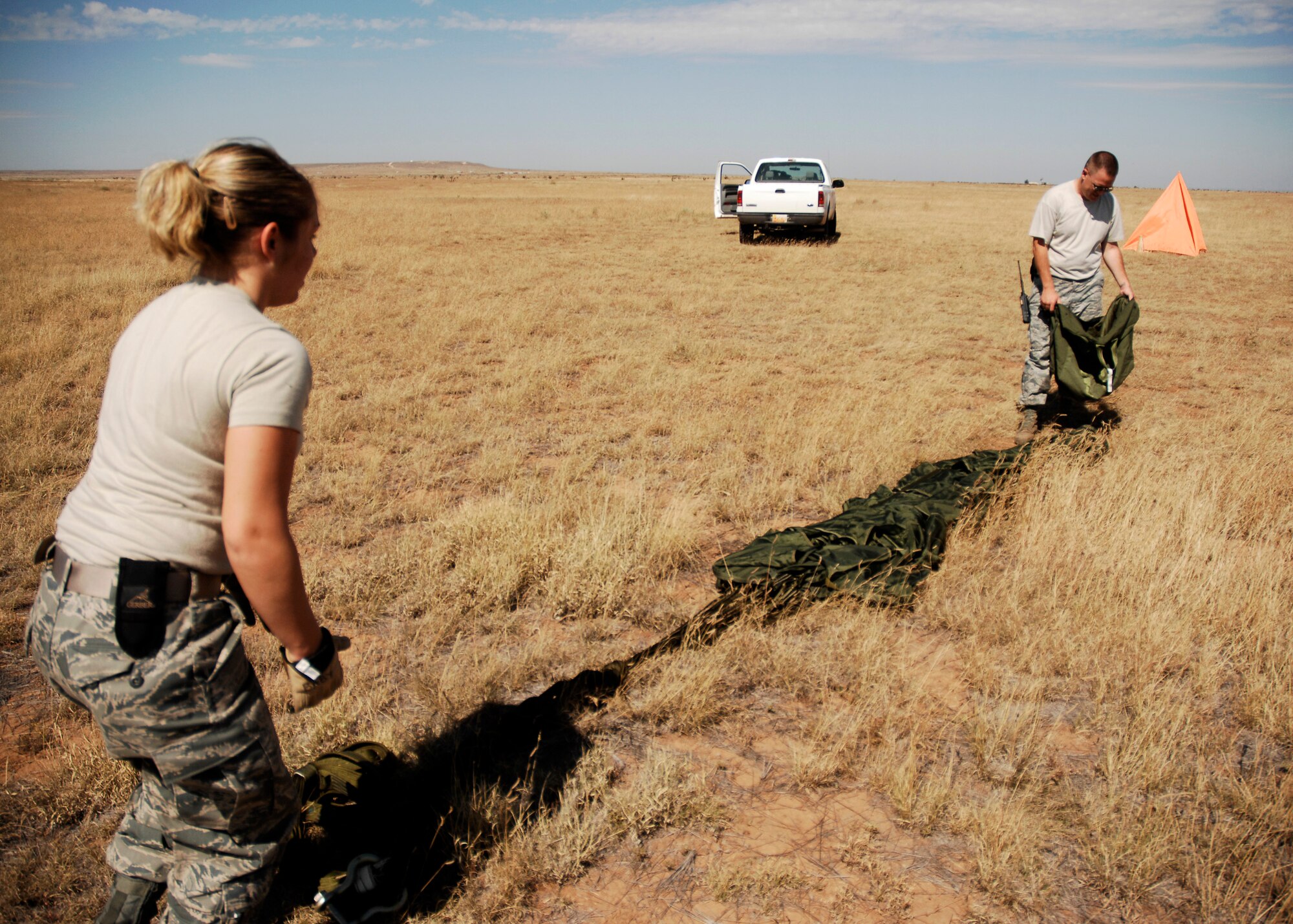 CANNON AIR FORCE BASE, N.M.-- Senior Airman Helen Eberly and Staff Sgt. Jerimy Pickering, 27th Special Operations Logistics Readiness Squadron, recover a parachute at the Melrose Air Force Range during an exercise Sept. 23. Airmen pack, inspect, and recover the loads that are used for airdrop training. (U.S. Air Force photo/Airman 1st Class Evelyn Chavez) 