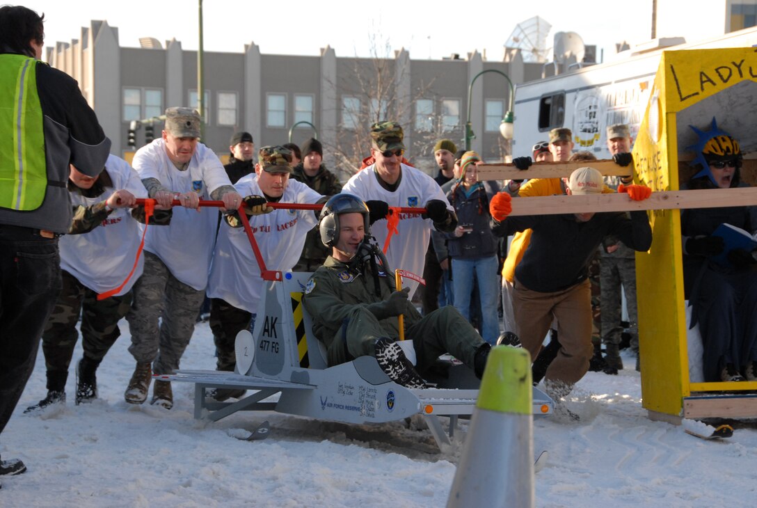 Members of the 477th Fighter Group push Col. Eric Overturf, 477th Fighter Group Commander, during "Outhouse Race" in the Anchorage, Alaska Fur Rondy celebration on February 24. (U.S Air Force Photo by Capt. Torri White)