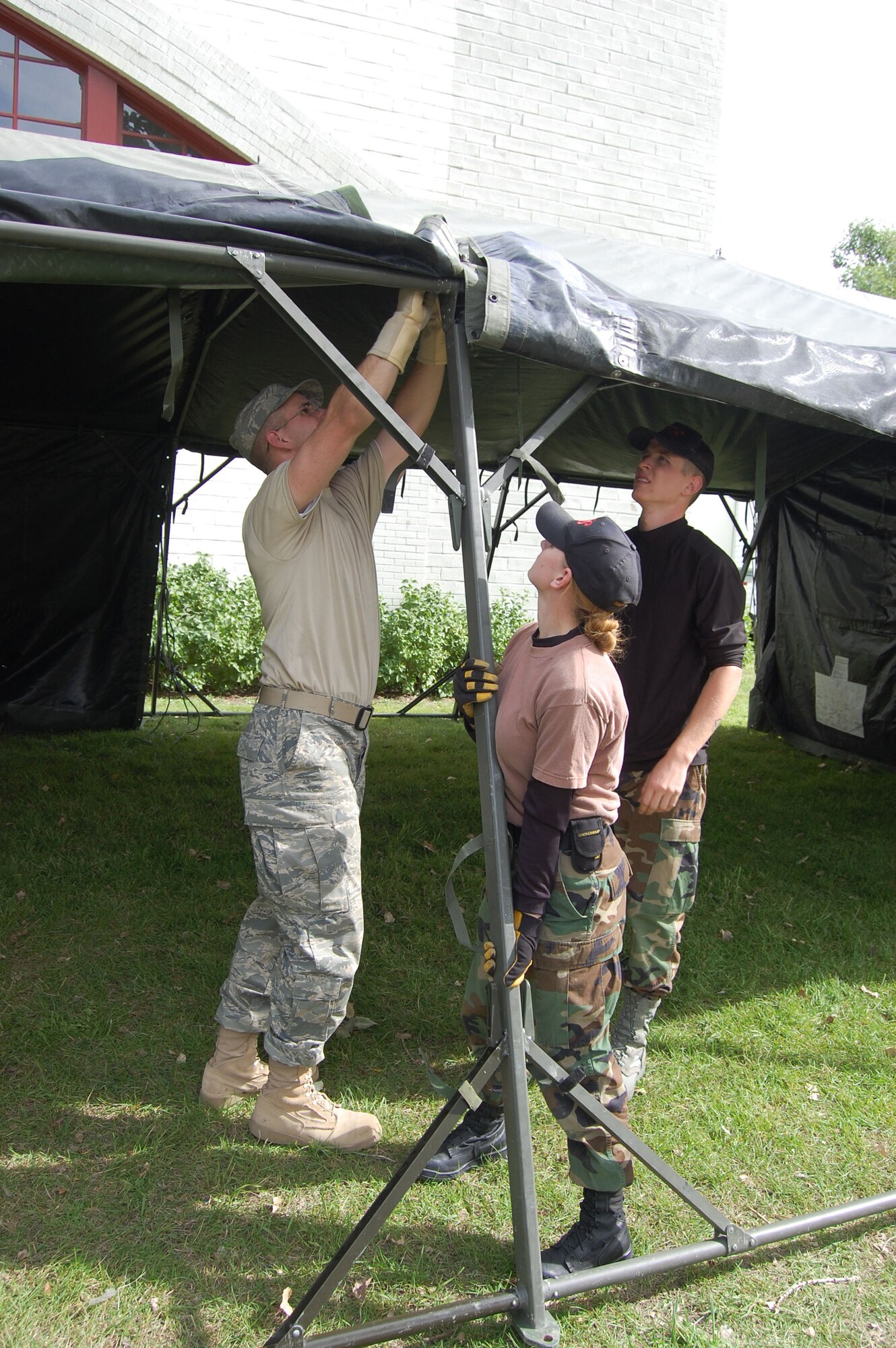 Staff Sgt. Michelle Springer holds a tent pole for Staff Sgt. Brian Rugg (left), as Airman 1st Class Caleb Storlie (right), makes sure the tent straps hold while they assemble the tent.  About a dozen members of the 341st Civil Engineer Squadron volunteered their time and effort to assemble military tents at the Great Falls Fair Grounds Sept. 25.  The tents and volunteers came from Malmstrom Air Force Base to support the second annual “Stand Down,” an event geared toward helping homeless veterans receive free medical check-ups, military clothing and supplies, and a free meal.    (U.S. Air Force photo/Senior Airman Eydie Sakura)