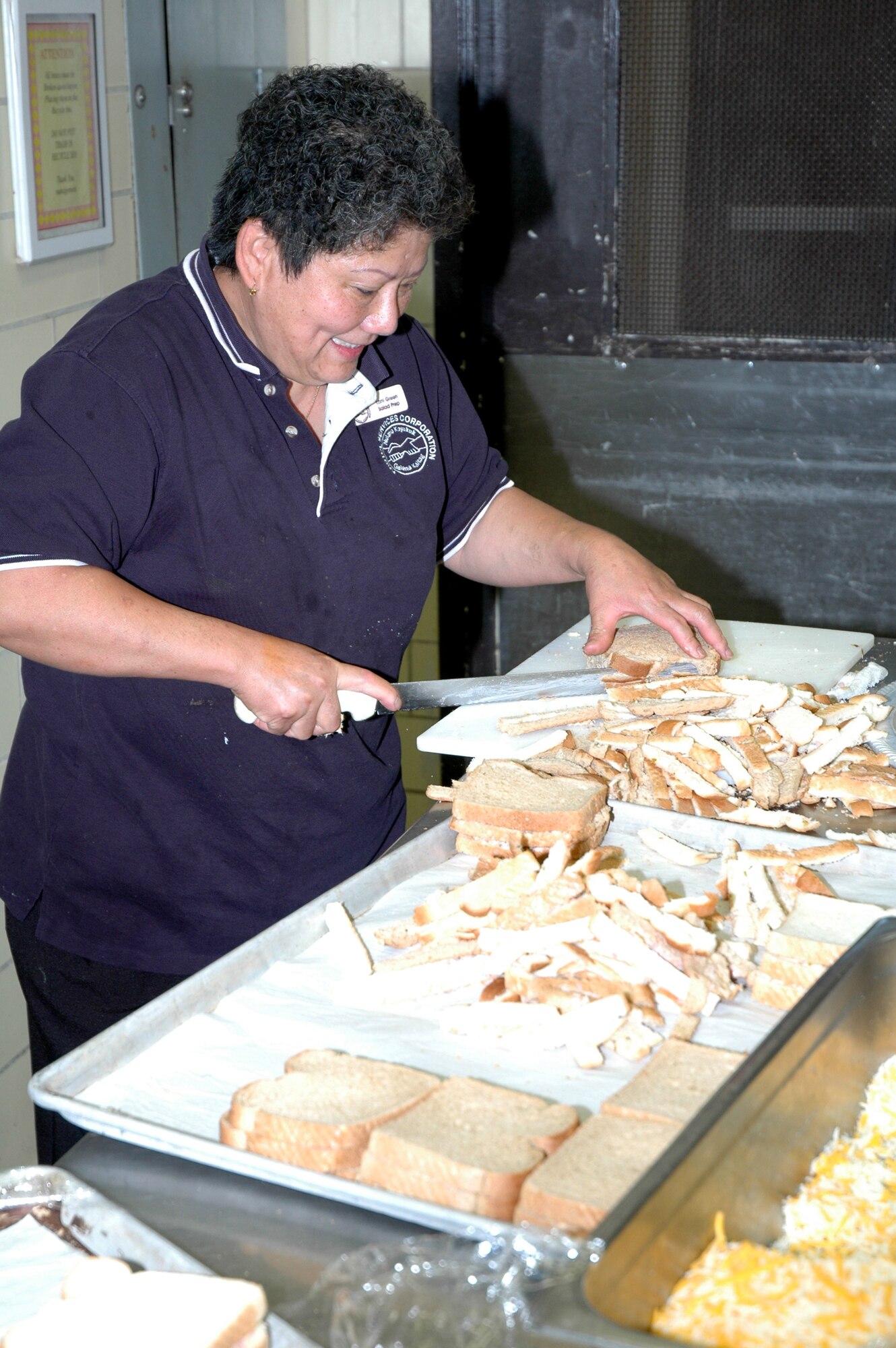 Loni Green, Grizzly Bend prepatory cook, cuts sandwiches  to restock buffet tables during the grand reopening of the club Sept. 26. Loni helped prepare 600 sandwiches, 60 pounds of meatballs, 30 pounds of potato skins, 40 pounds of beef brisket and 15 dozen deviled eggs in the course of nine hours. (U.S. Air Force photo/Airman 1st Class Dillon White)