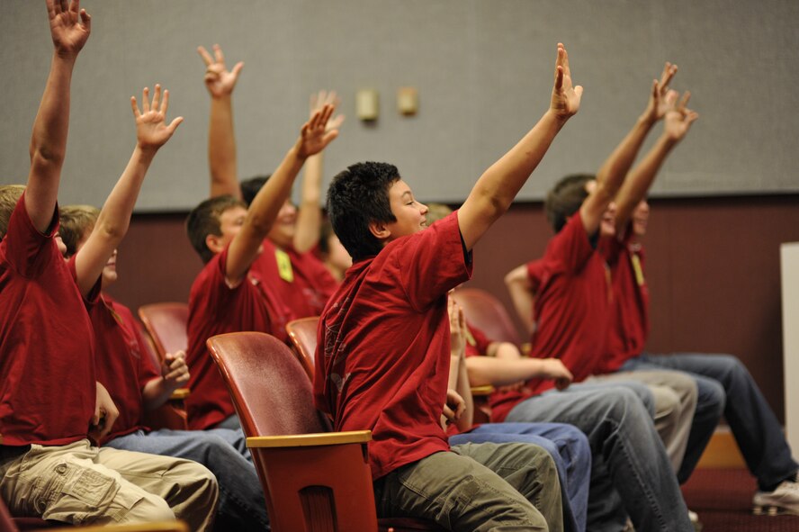 A group of anxious eighth-grade boys raise their hands to answer questions by the tour briefers at the Main Auditorium during the tour. (Photo by Rick Goodfriend)