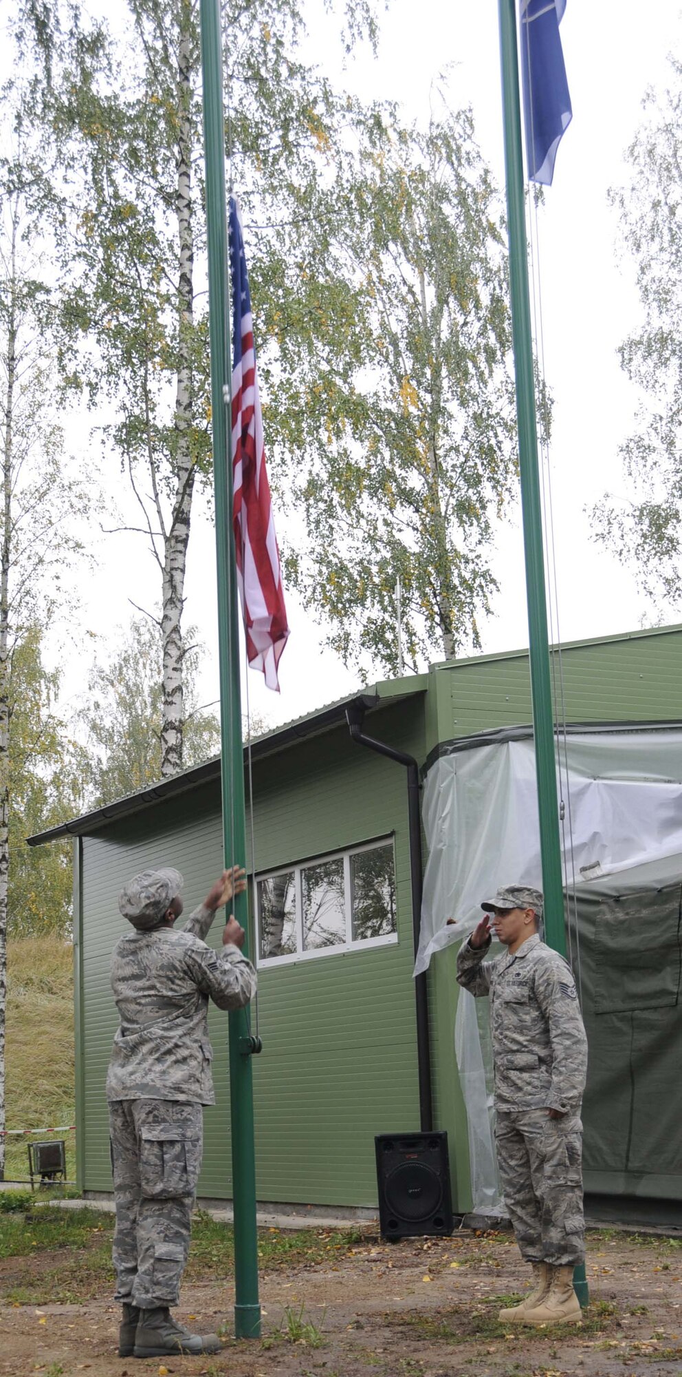Senior Airman Antonio Huguley, 493d Expeditionary Fighter Squadron PERSCO, 493d EFS Quality Assurance, raise the U.S. flag over the Quick Reaction Facility as Staff Sgt. Raphael Santos-Montanez salutes the colors.  The flag raising was a part of the change-over ceremony marking the first day of the U.S. rotation performing the NATO Baltic air policing mission.  (U.S. Air Force photo by Tech. Sgt. Jill Lavoie))