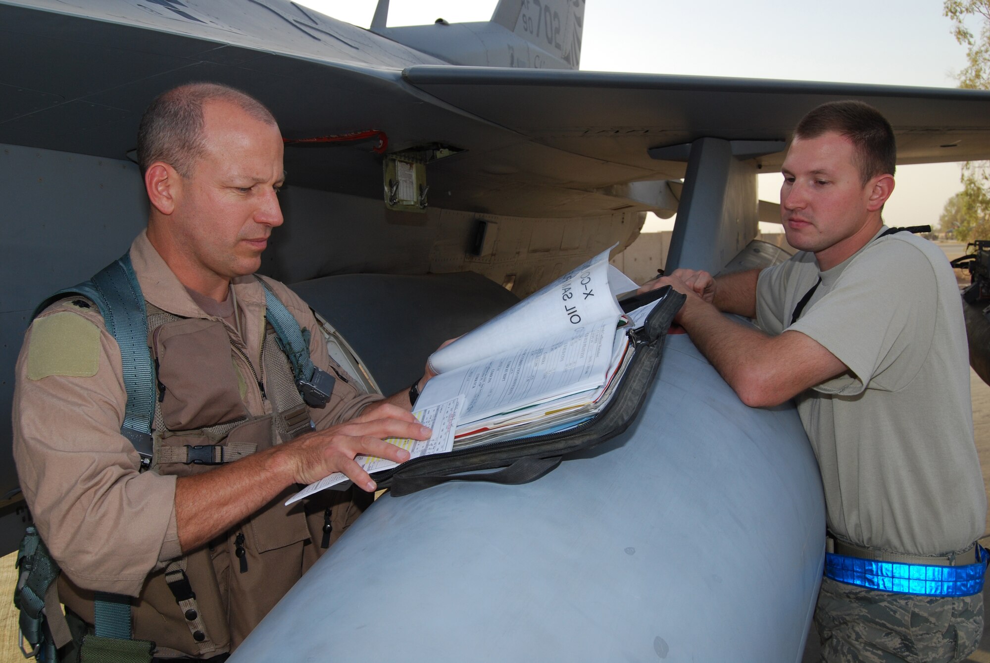 Lt. Col. David Serage and Staff Sgt. Jared Price review the maintenance records of Serage's F-16 Fighting Falcon at Joint Base Balad, Iraq, before a mission Oct. 2. Serage flew his 100th combat sortie since joining the Air Force in 1989. Serage, an instructor pilot with the 332nd Expeditionary Fighter Squadron, is deployed from the Air National Guard's 138th Fighter Wing in Tulsa, Okla. (U.S. Air Force photo/Staff Sgt. Don Branum)
