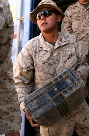 Pfc. Paul J. Casoose, an ammunition specialist technician with Headquarters and Service Company, 1st Light Armored Reconnaissance Battalion, Regimental Combat Team 5, hands off 25mm ammunition to Marines of Company D, 1st LAR Bn. before they leave on a patrol at Camp Korean Village, Iraq. With the Iraqi Security Forces providing the majority of security in al-Anbar province, 1st LAR Bn. will assist the ISF by patrolling the open desert to disrupt insurgent activity.::r::::n::