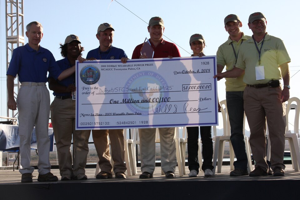 Team DuPont/SFC Smart Fuel Cell M-25 receives a first place winning prize of $1 million from Dr. William S. Rees, Jr., deputy under the Secretary of Defense for Laboratory and Basic Sciences. The award was for the 2008 Directory Defense Research and Engineering’s Wearable Power Prize competition, one that tested endurance of portable power sources for military use. The open-gate award ceremony was held at Del Valle Field aboard the Marine Corps Air Ground Combat Center in Twentynine Palms, Calif., Oct. 4, 2008.