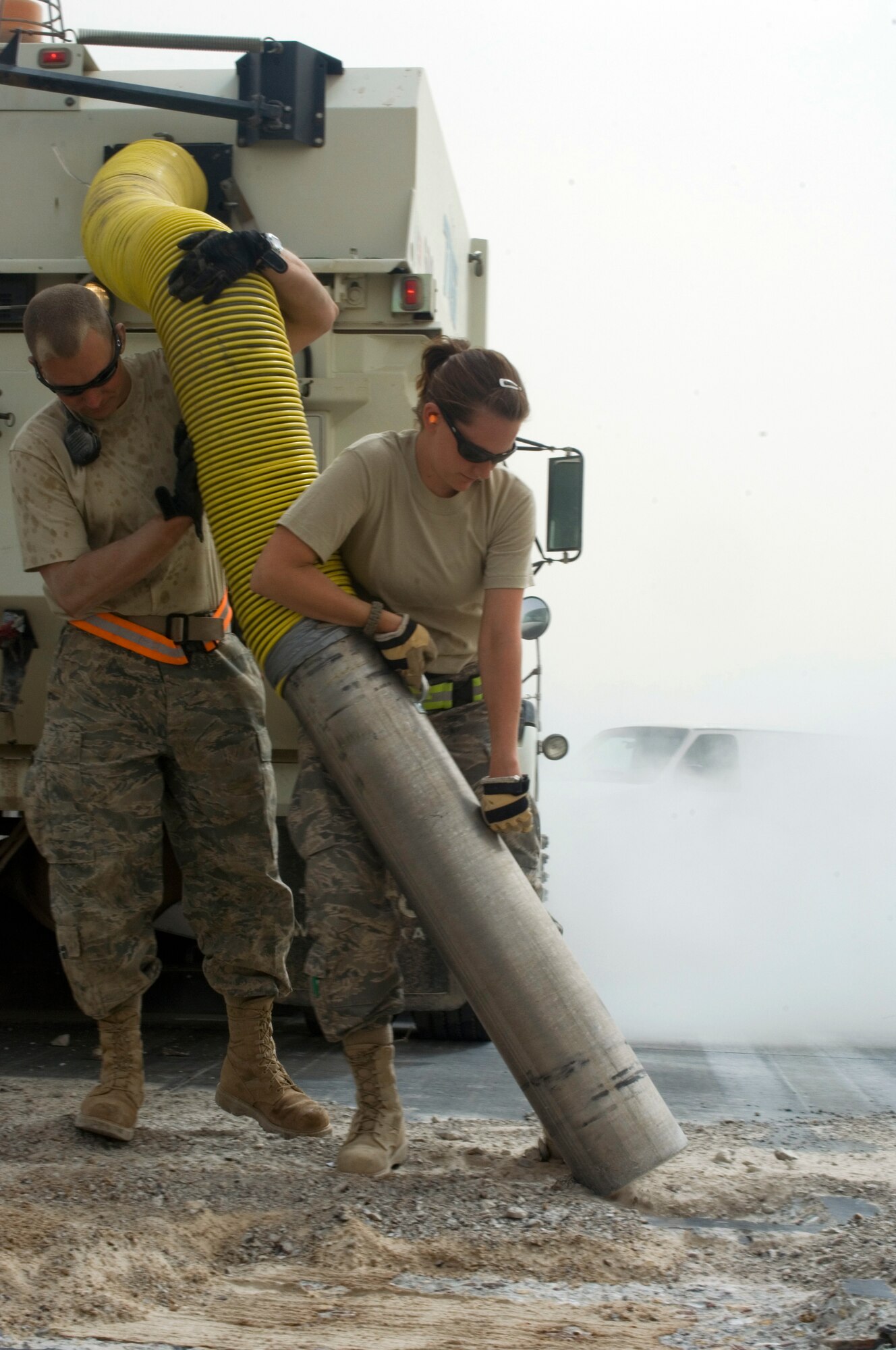 Tech. Sgt. Mark Day and Staff Sgt. Cassandra Baker use a vacuum to clear debris from broken up sections of runway at Joint Base Balad, Iraq, Oct. 2. Both Airmen are deployed to the 332nd Expeditionary Civil Engineer Squadron from Misawa Air Base, Japan. Day?s hometown is Abilene, Texas, and Baker?s hometown is Mashpee, Mass. (U.S. Air Force photo/Tech. Sgt. Erik Gudmundson)